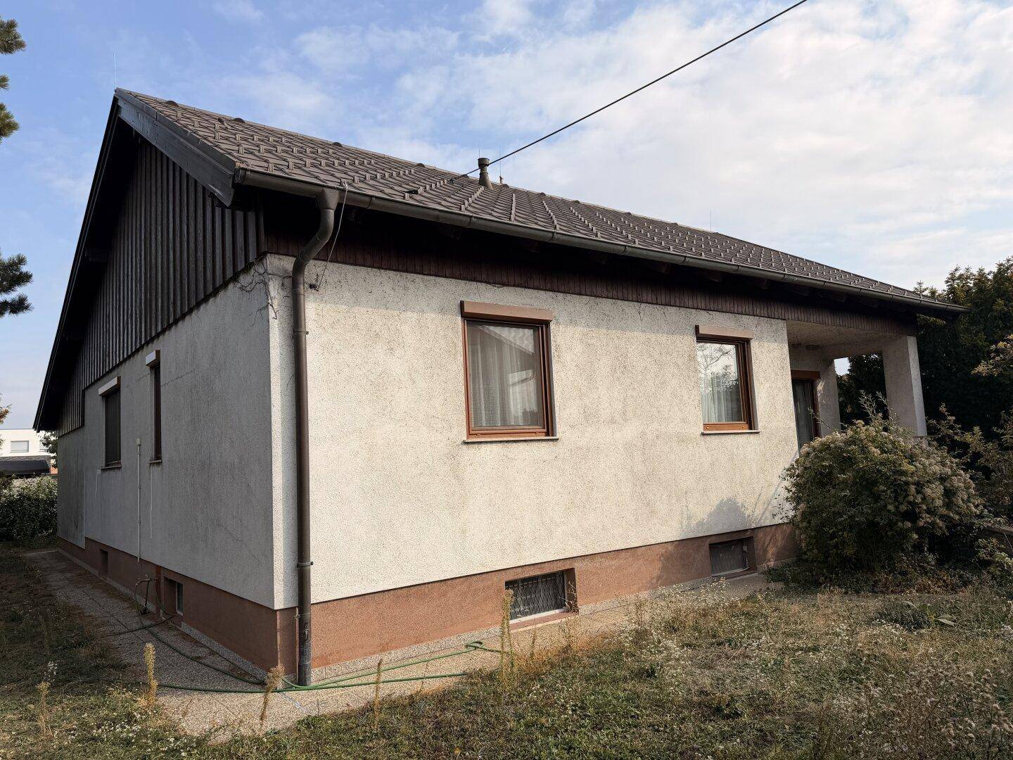 Gesamtansicht des Einfamilienhauses mit Satteldach und umliegendem Gartenbereich.