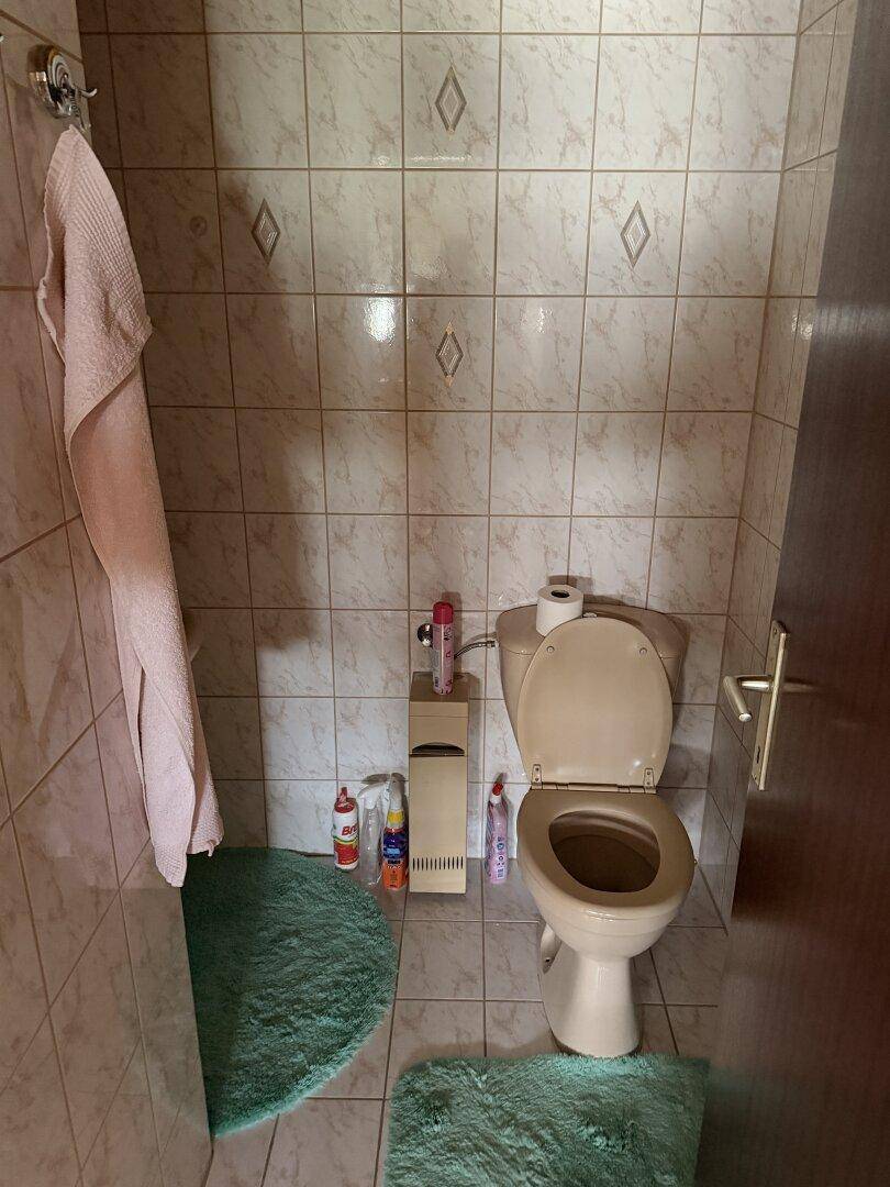 Kleines Gäste-WC mit beigefarbenen Fliesen und einfacher Ausstattung.