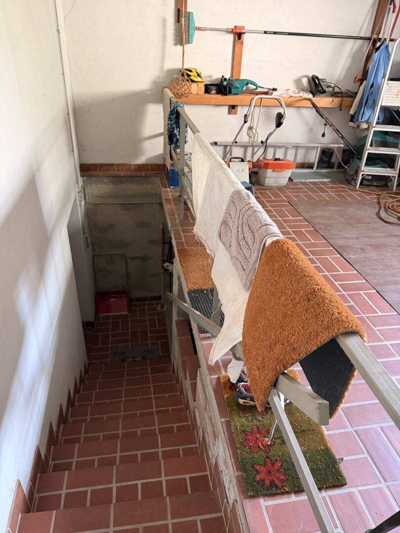 Kellertreppe mit Terrakotta-Fliesen und Geländer, die zu einem weiteren Kellerbereich führt.