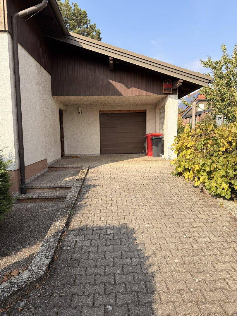 Einfahrt zum Haus mit gepflastertem Weg und integrierter Garage.