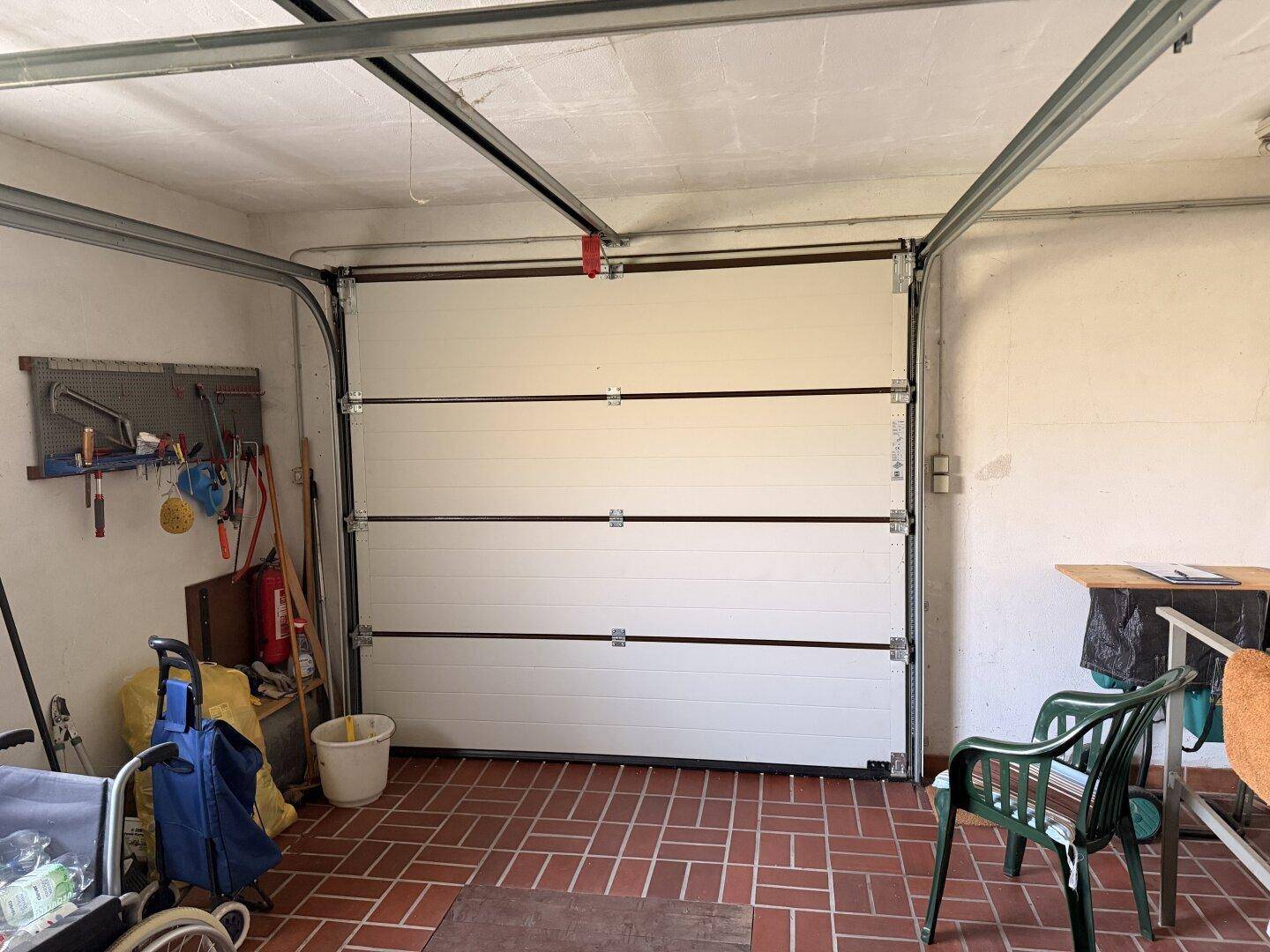 Innenansicht der Garage mit Sektionaltor und praktischem Stauraum.