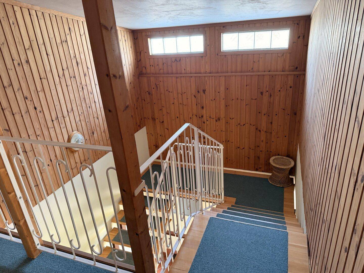 Treppenhaus mit Holzvertäfelung und Geländer, das zu den oberen Etagen führt.