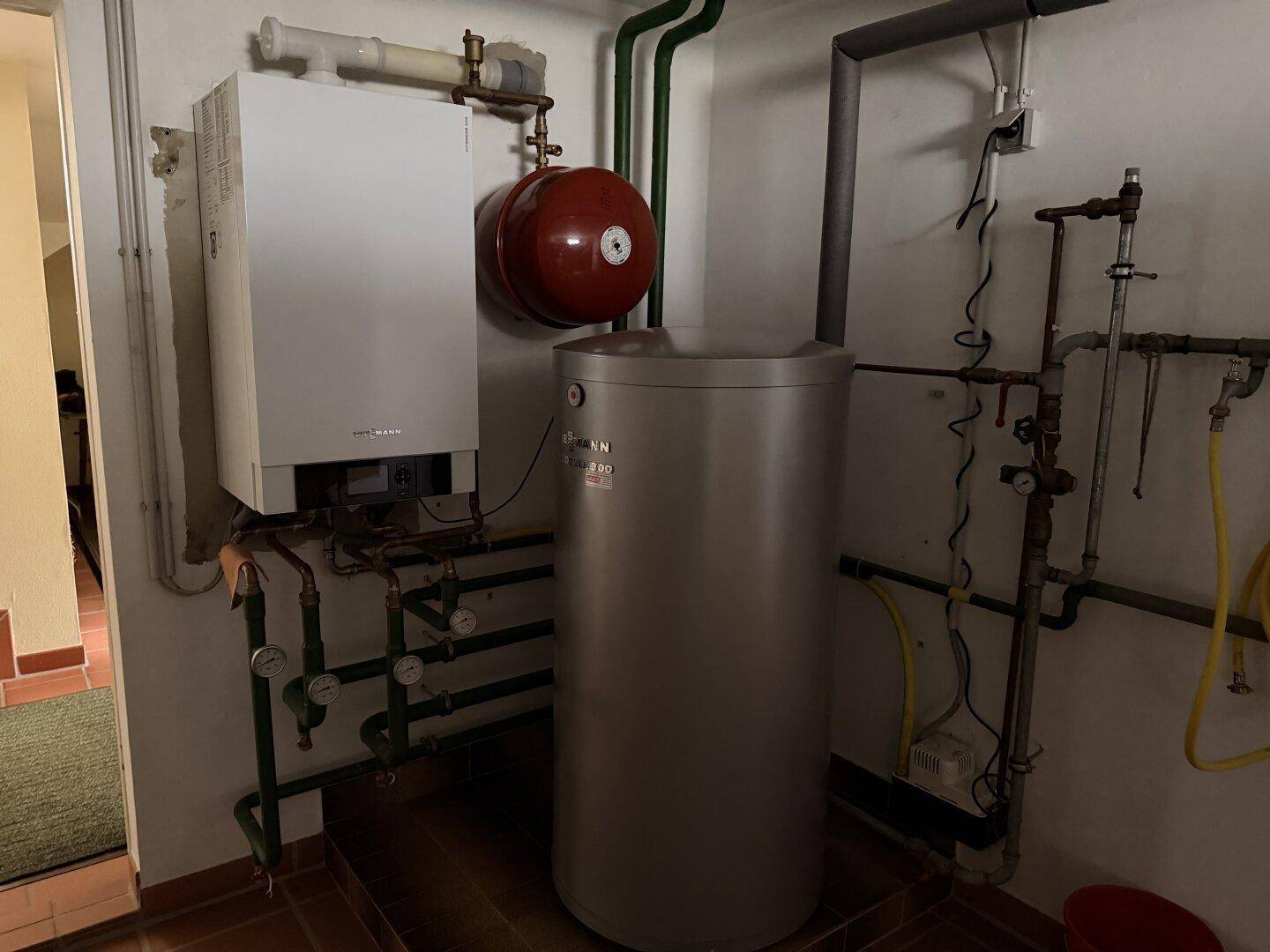 Heizungsraum im Keller mit moderner Heizungsanlage und Warmwasserspeicher.