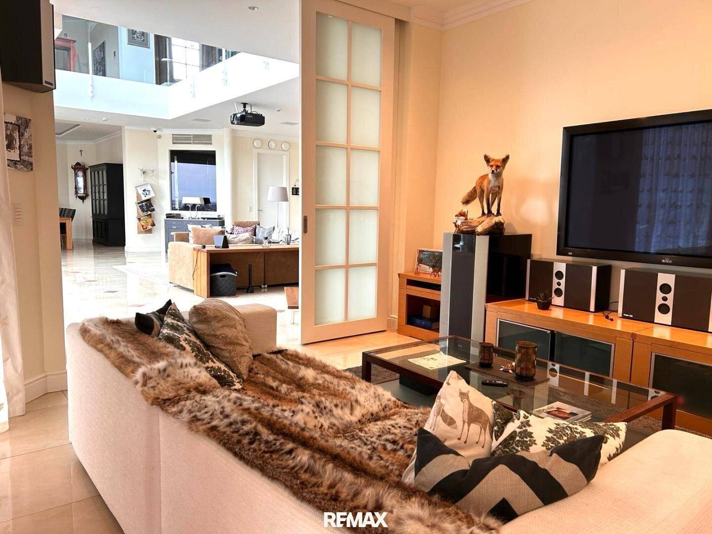 Gemütlicher Wohnbereich mit bequemer Couch, Fernseher und Blick in den offenen Hauptwohnbereich.