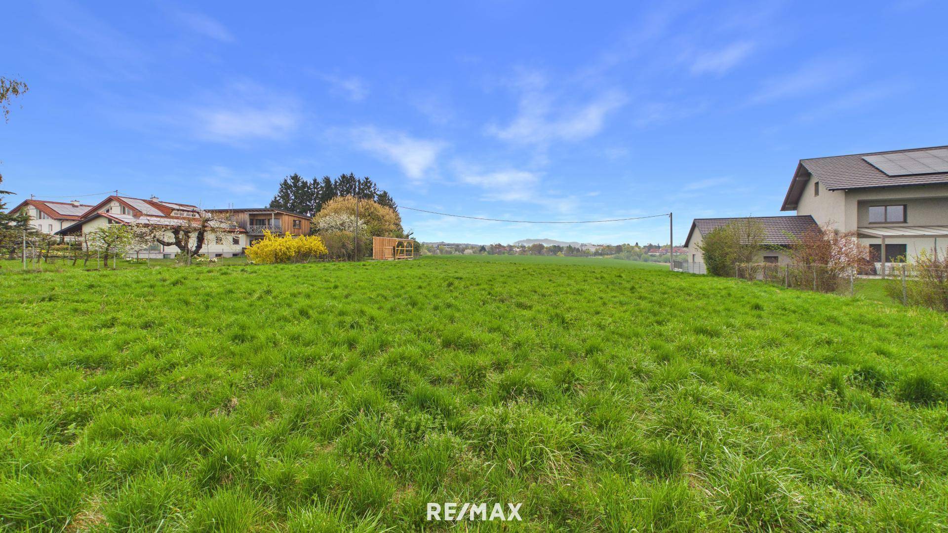 Ausgedehnte grüne Wiese umgeben von Wohnhäusern mit Blick auf die hügelige Landschaft.