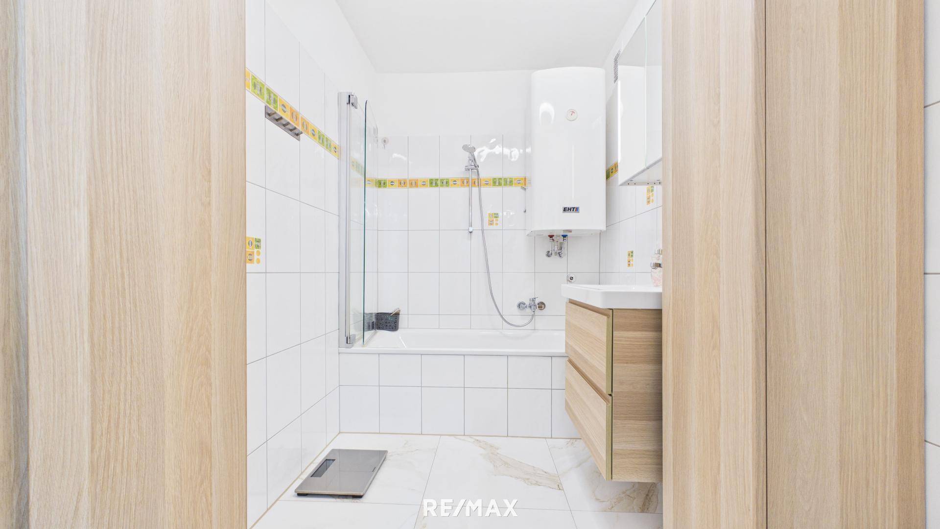 Modernes Badezimmer mit Badewanne, Dusche und hellem Fliesenboden.