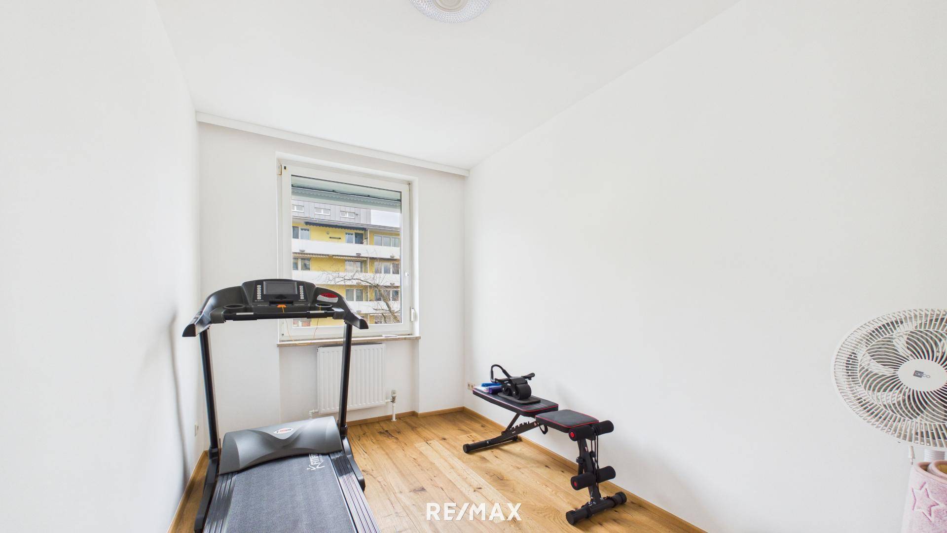Fitnessraum mit Laufband, Hantelbank und Holzboden, ideal für das Heimtraining.
