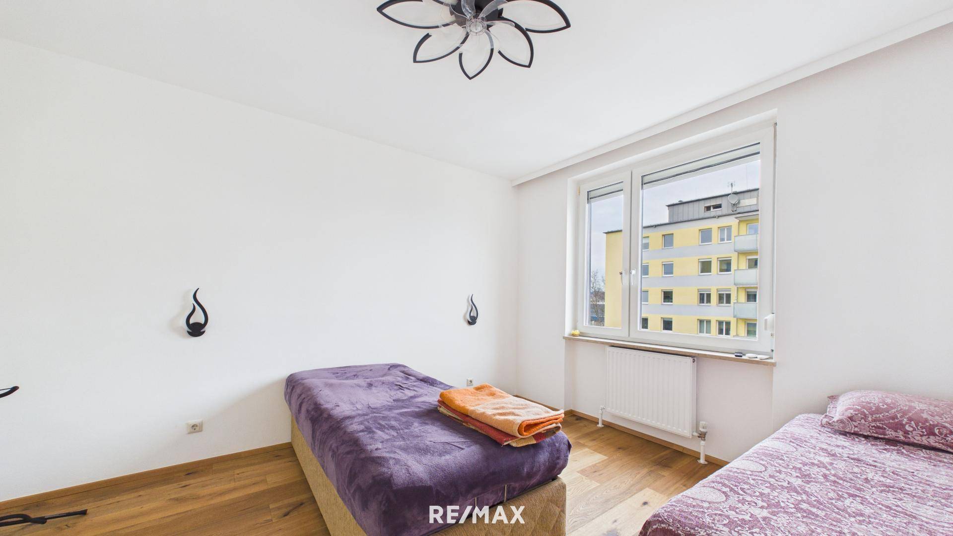 Helles Schlafzimmer mit Holzboden, zwei Betten und Fenster mit Blick nach draußen.