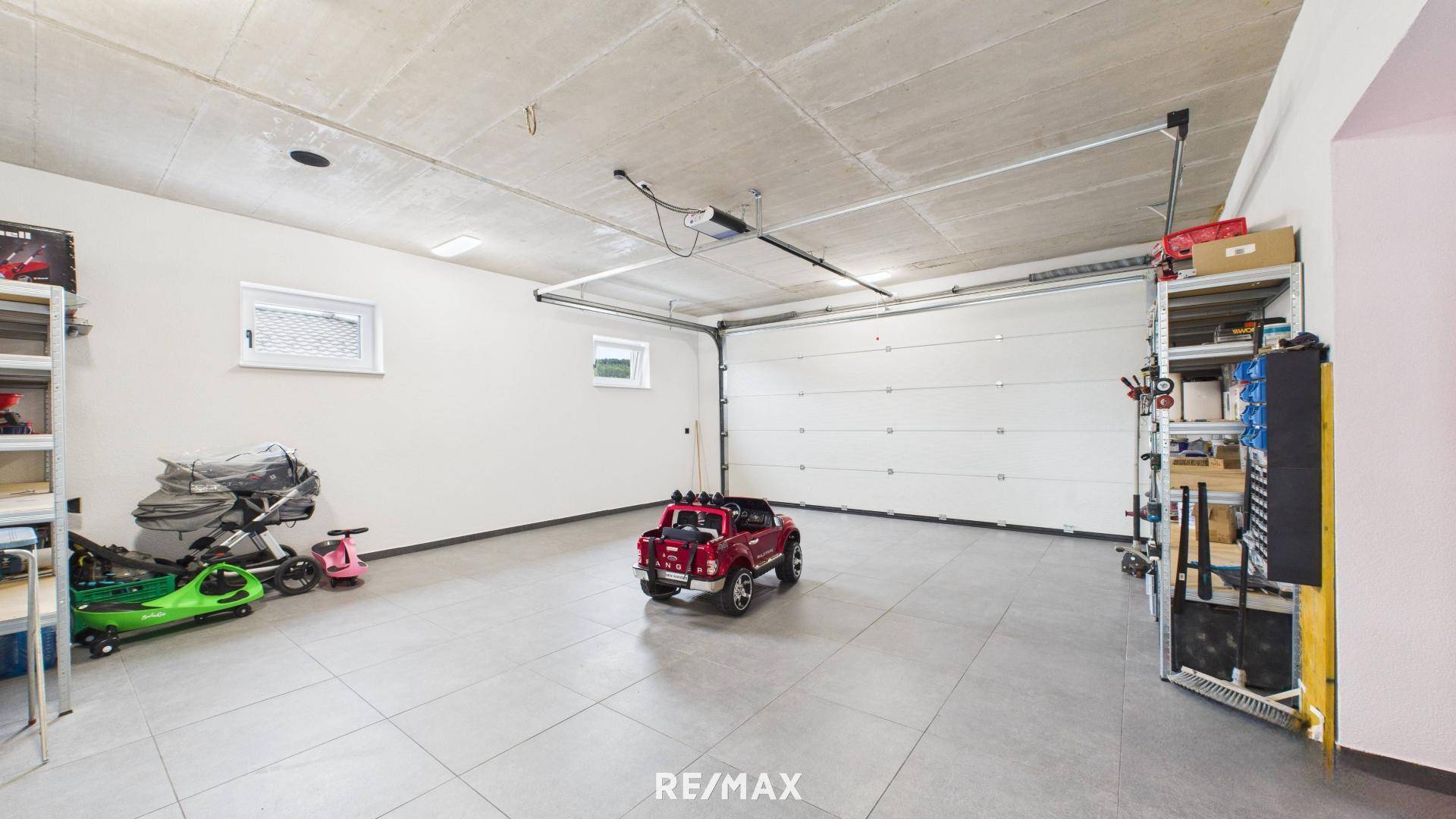 Geräumige Garage mit Fliesenboden, automatischem Garagentor und viel Stauraum.
