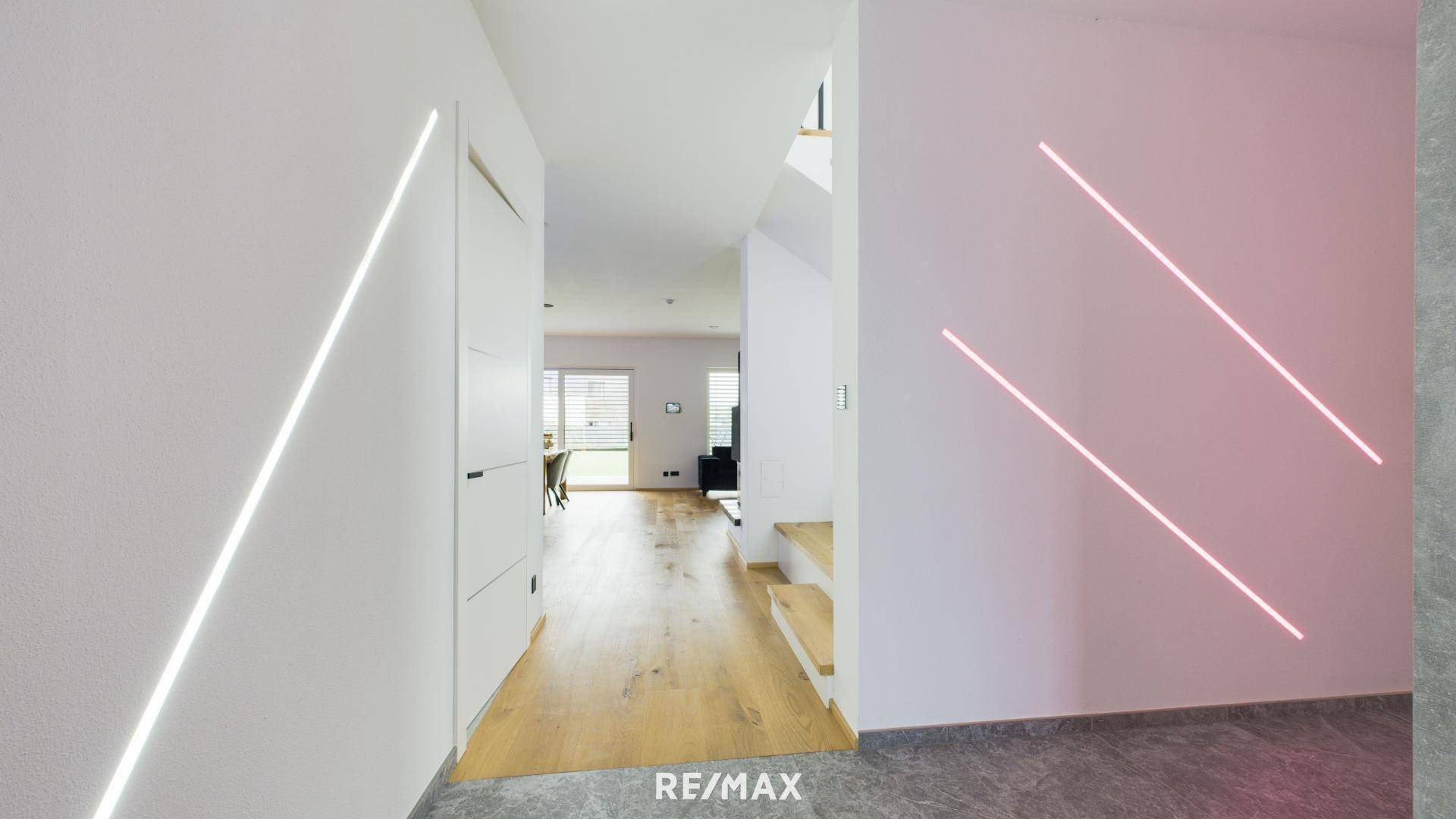 Heller Flur mit modernen Lichtleisten an den Wänden und einer Kombination aus Fliesen- und Holzboden.