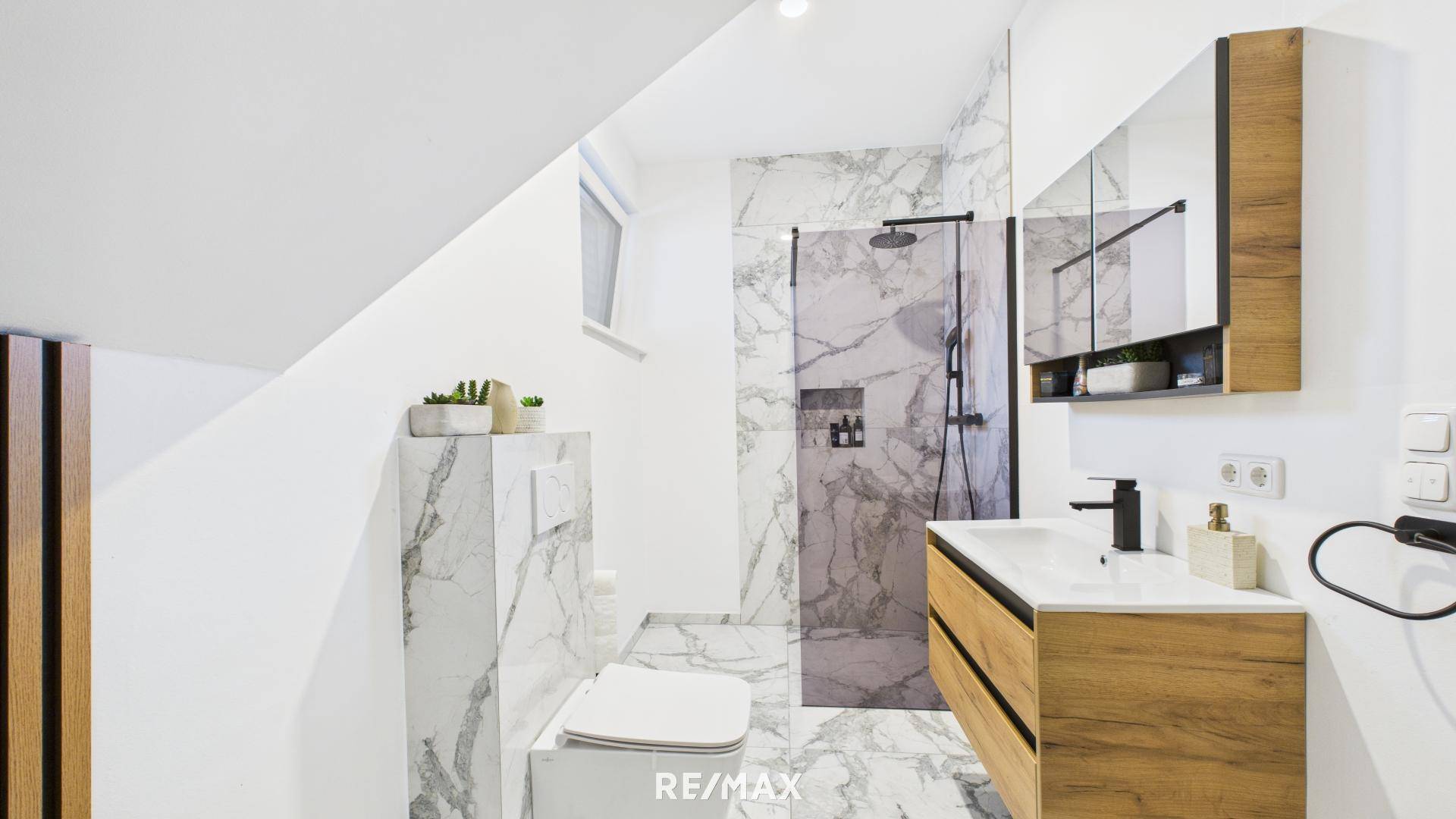 Elegantes Badezimmer mit Marmorfliesen, Holzwaschtisch und großer Duschkabine mit Regendusche.