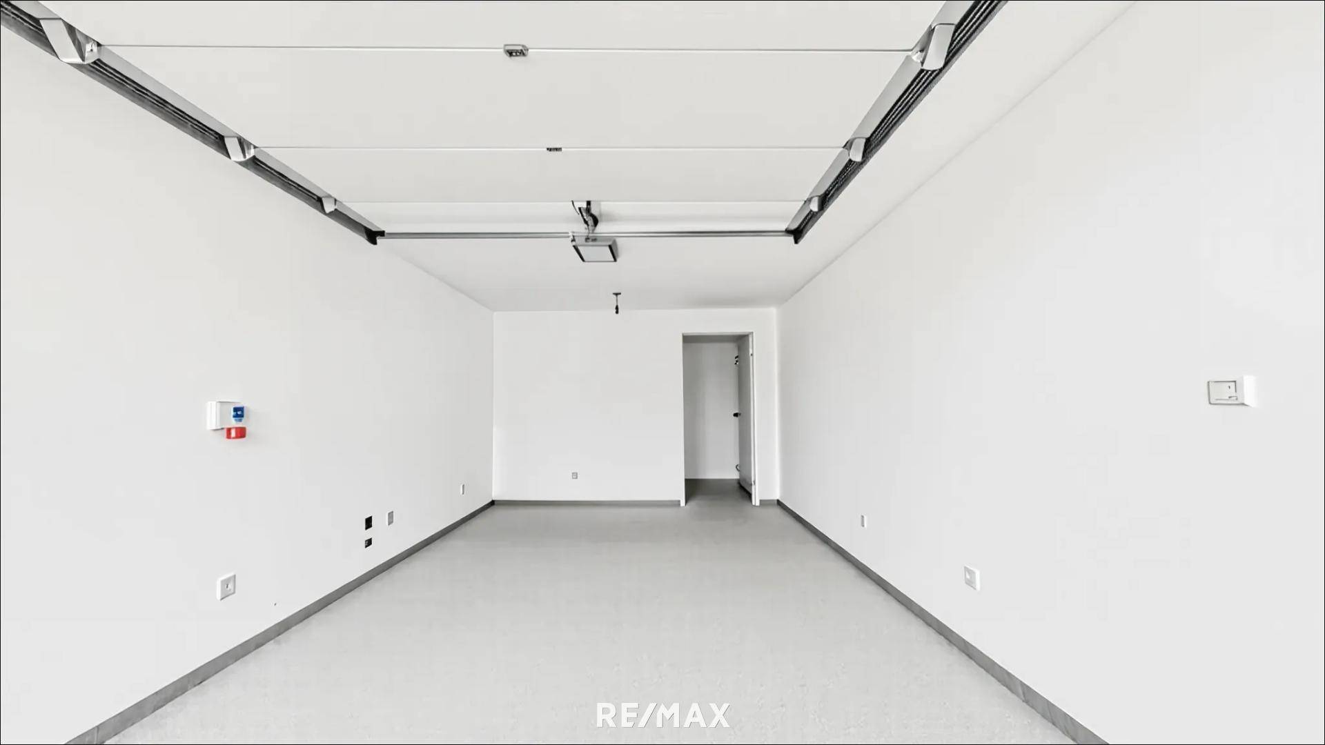 Leerer, heller Raum mit weiß gestrichenen Wänden und einfacher Beleuchtung, bereit zum Ausbau.
