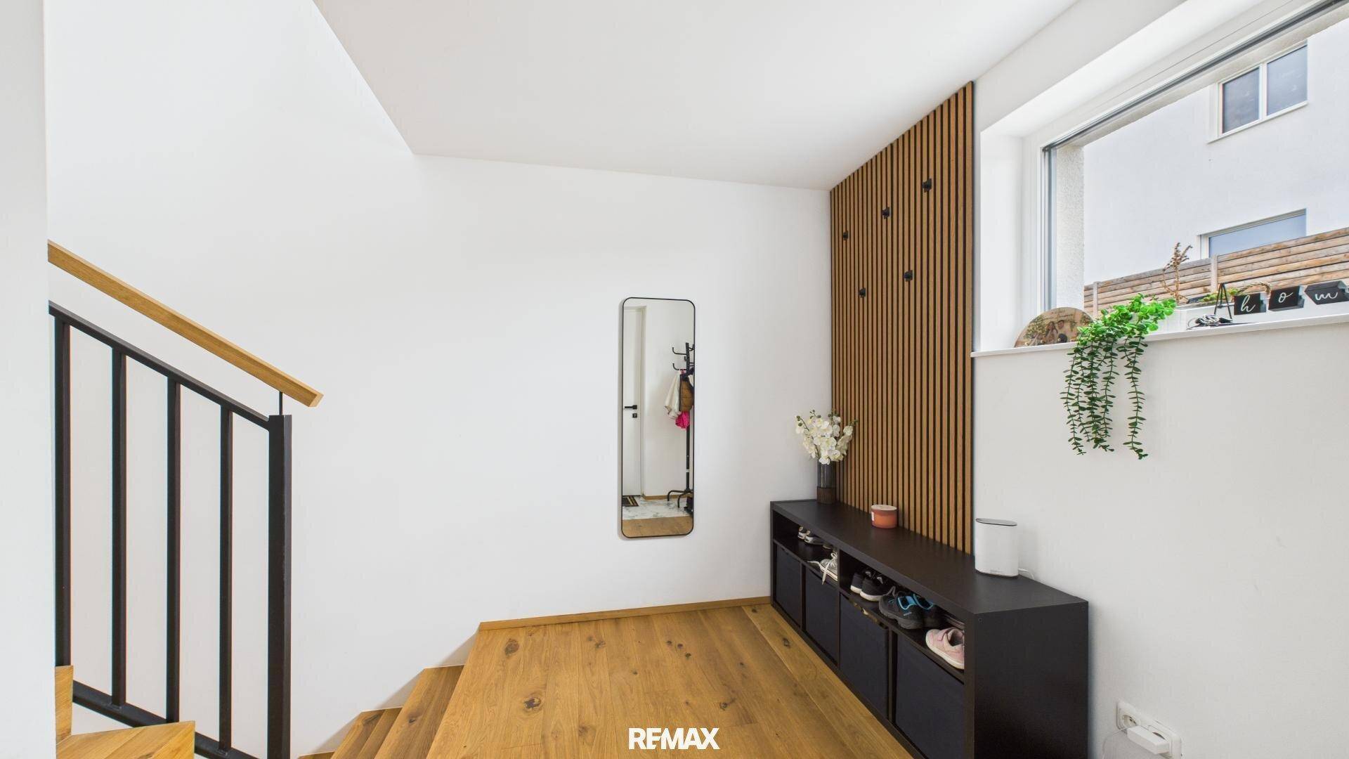Heller Eingangsbereich mit Holztreppe, modernem Schuhschrank und dekorativer Wandverkleidung.