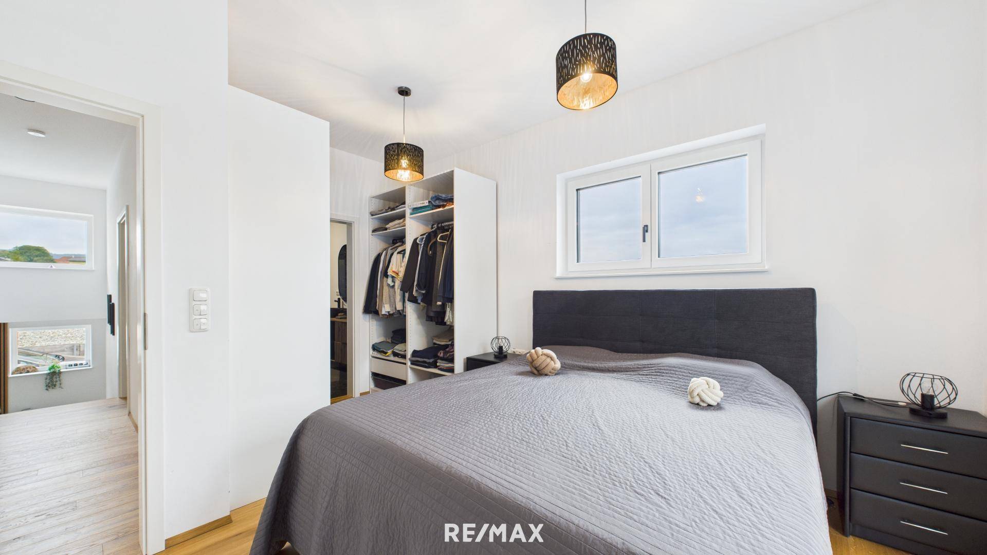 Komfortables Schlafzimmer mit Doppelbett und offenem Zugang zu einem begehbaren Kleiderschrank.