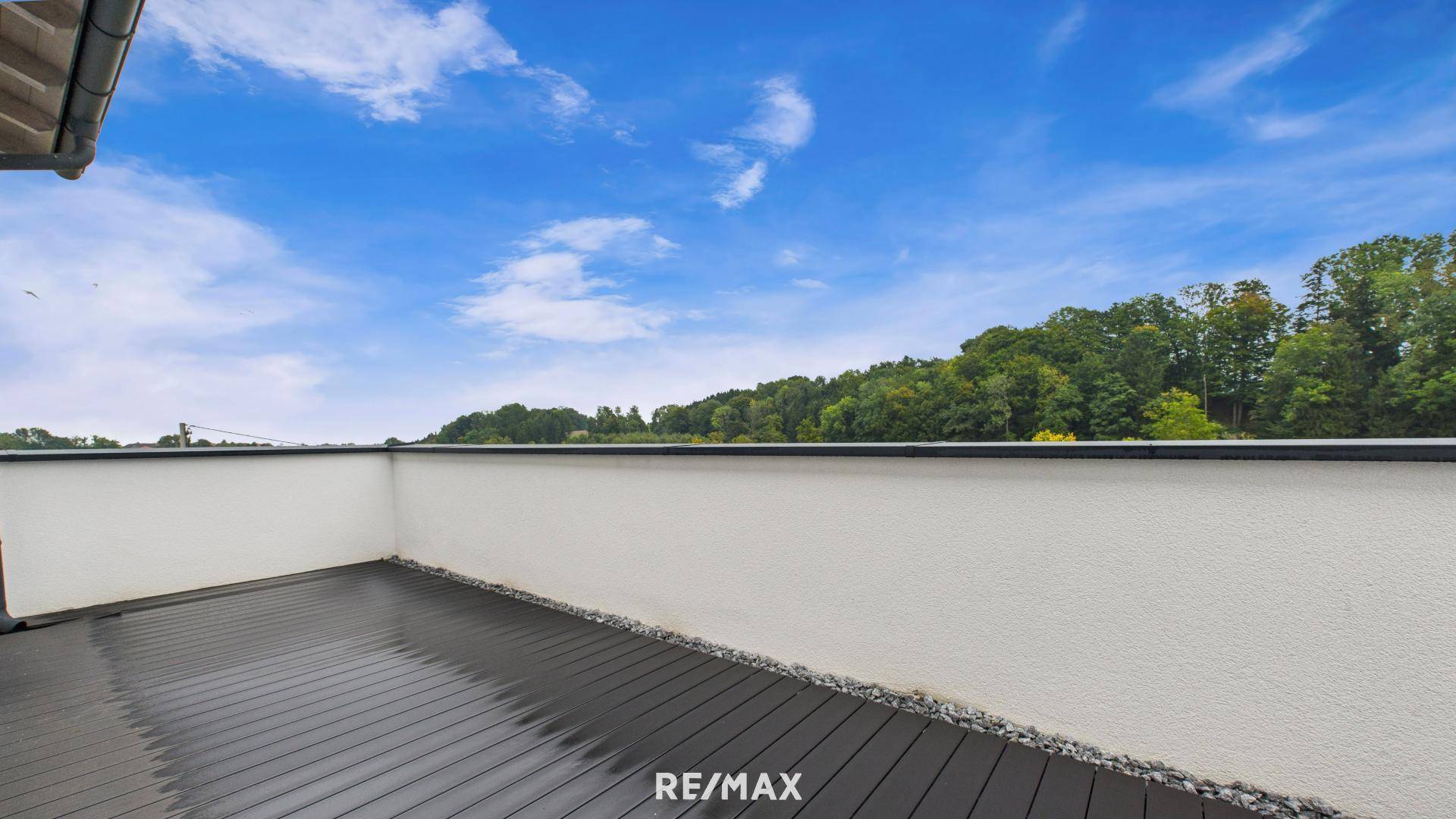 Geräumiger Balkon mit dunklem Bodenbelag und weitem Blick auf die grüne Landschaft.