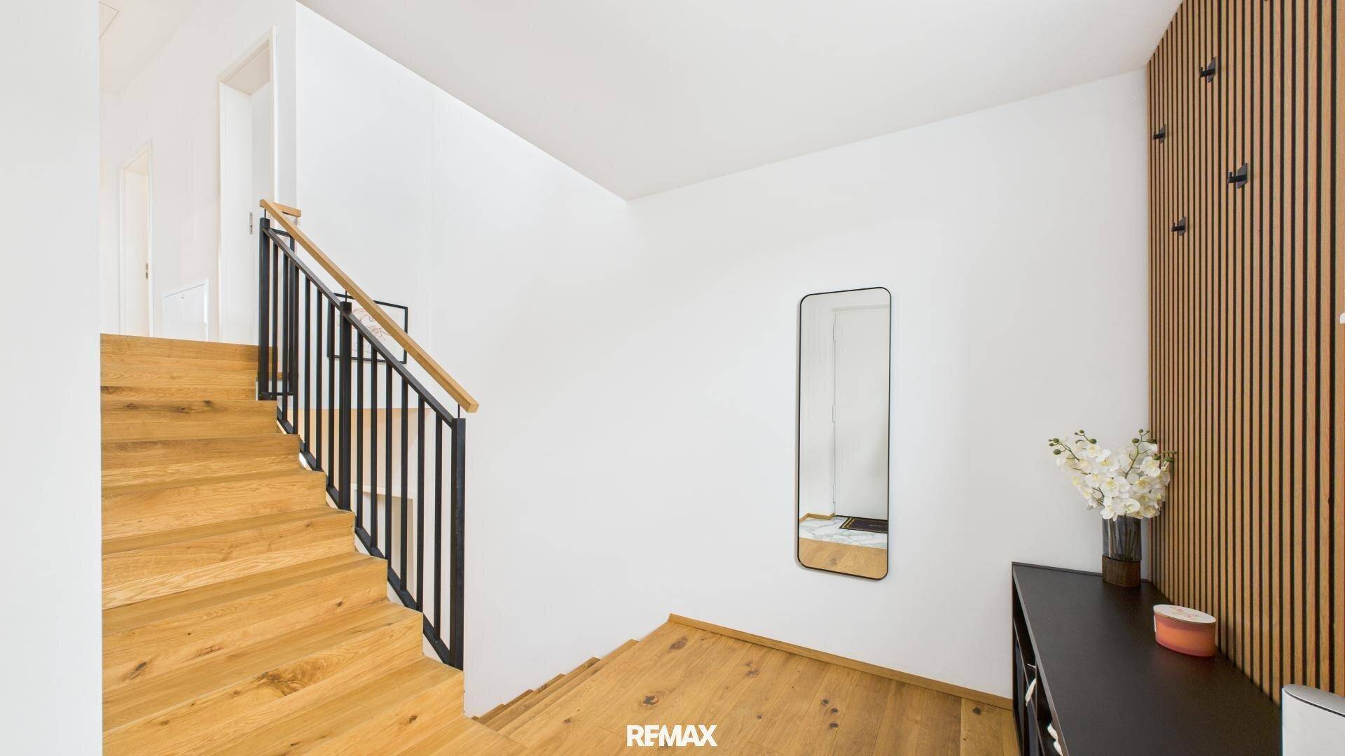 Geräumiger Flur mit offener Holztreppe und minimalistischer Wandgestaltung.