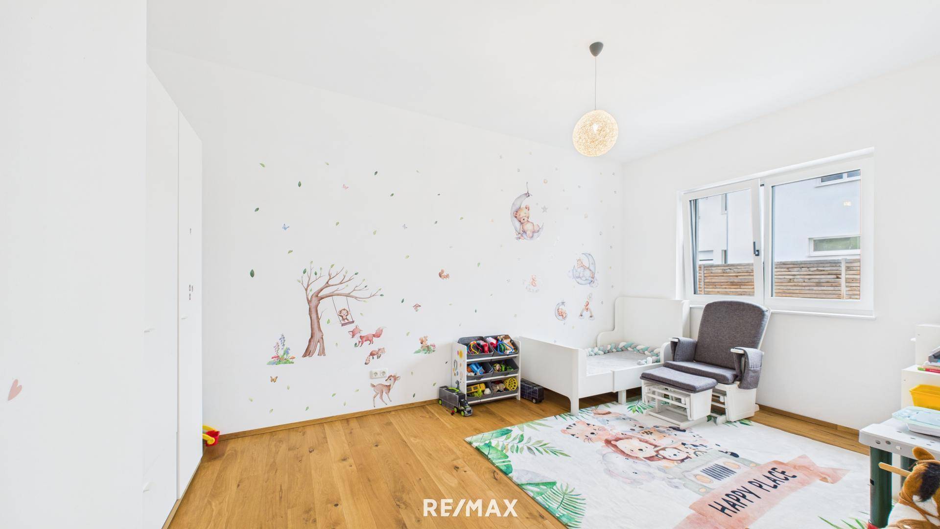 Gemütliches Kinderzimmer mit Holzboden, Kinderbett und liebevollen Wandstickern mit Tiermotiven.