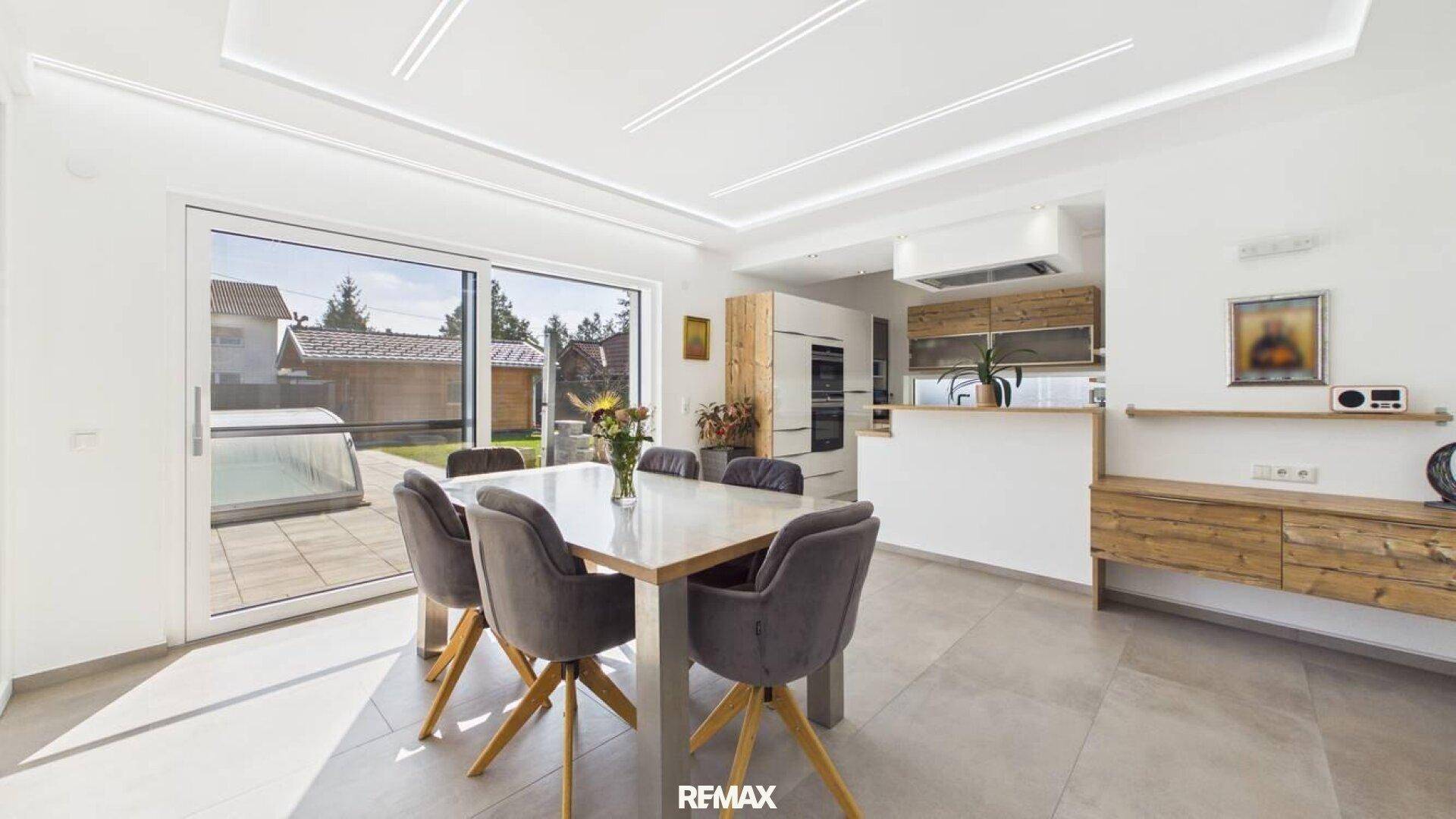 Heller Essbereich mit Zugang zur Terrasse und offener Küche im modernen Stil.