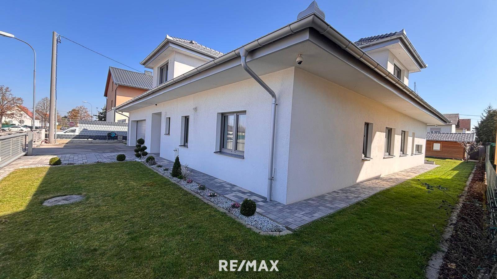 Modernes Einfamilienhaus mit gepflegtem Vorgarten und Rasenfläche.