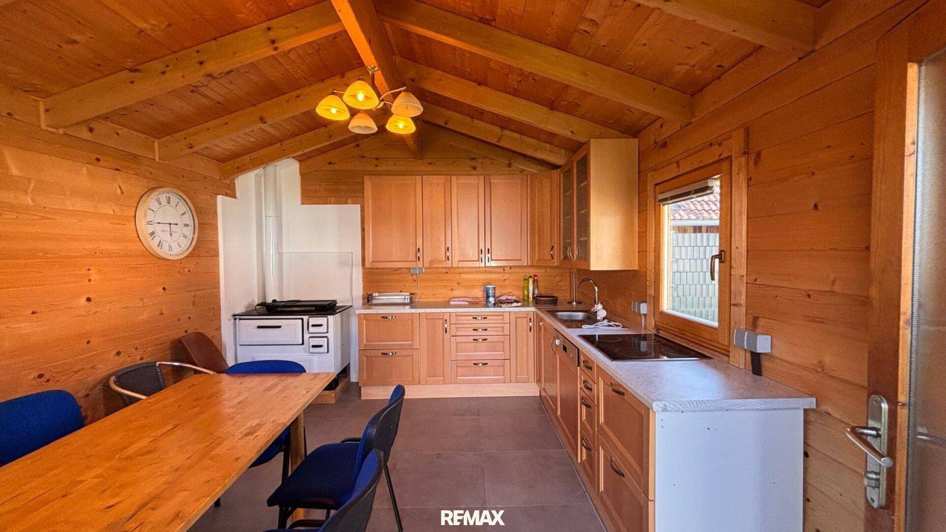 Rustikale Holzküche mit Esstisch und traditionellem Ofen in gemütlicher Atmosphäre.
