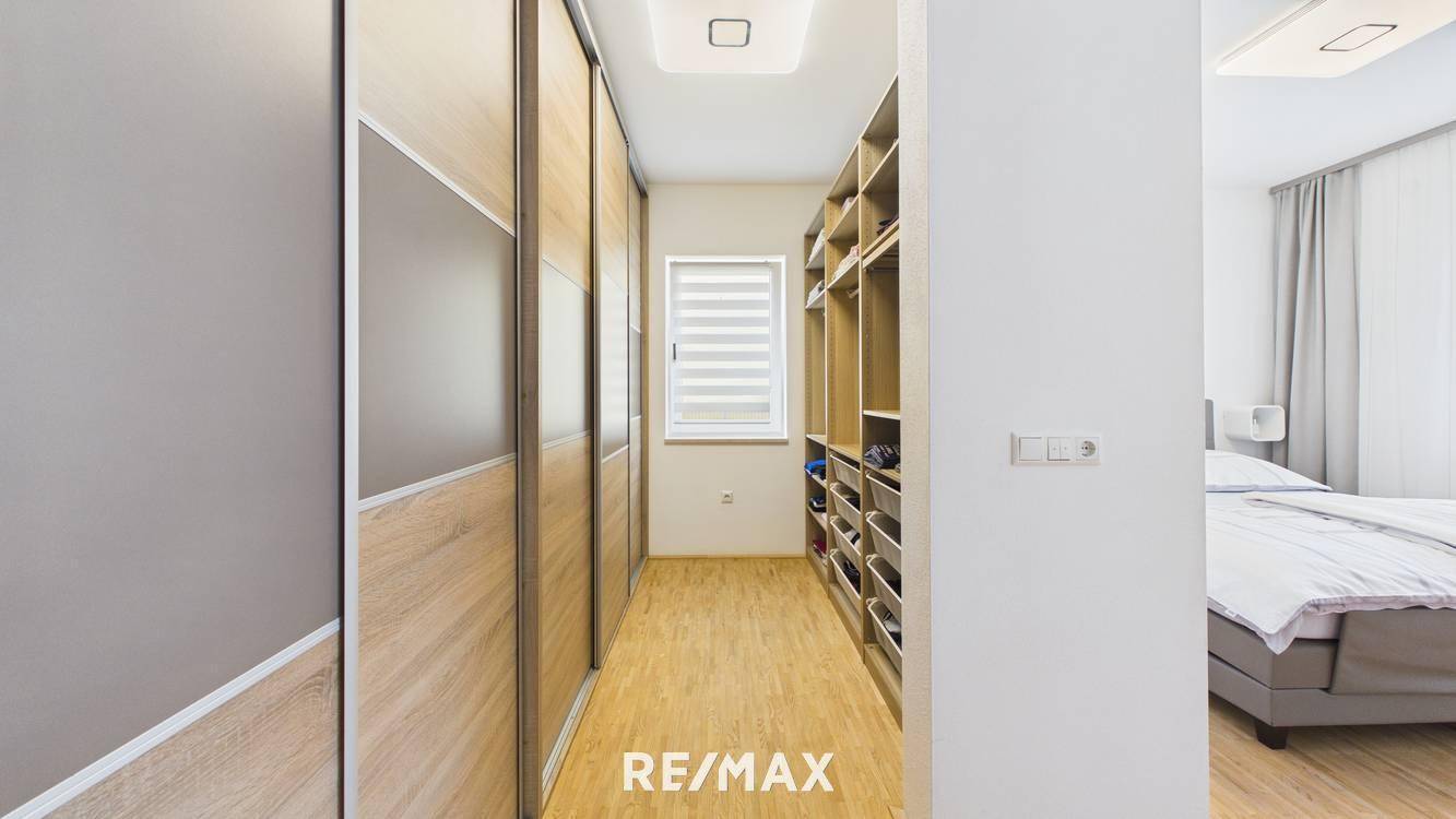 Geräumiger begehbarer Kleiderschrank mit viel Stauraum und Holzboden.