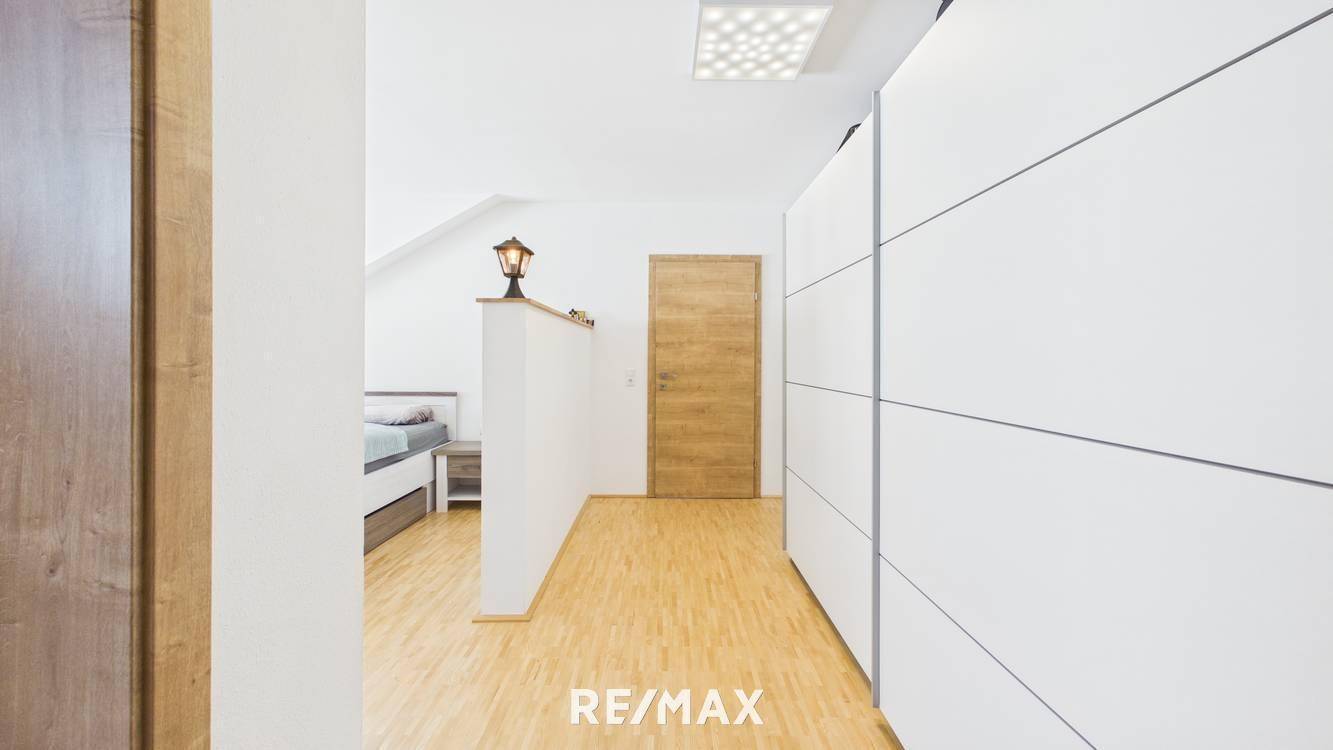 Heller Flur mit Einbauschränken und hellem Holzboden, der zu einem Schlafzimmer führt.