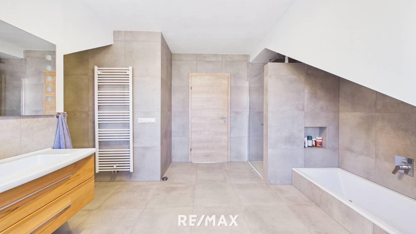 Geräumiges Badezimmer mit moderner Ausstattung, Badewanne, Dusche und beheiztem Handtuchhalter.