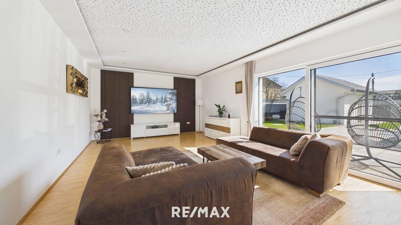 Großzügiges Wohnzimmer mit bequemen Sofas, Holzboden und Blick in den Garten.