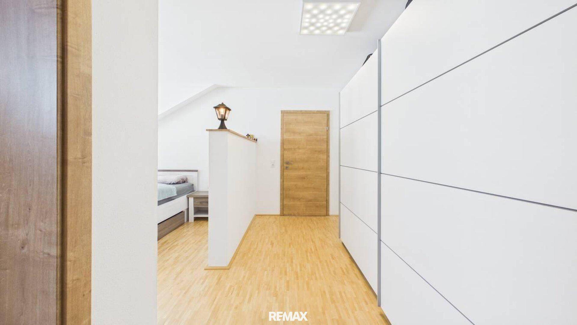 Schlafzimmer mit hellem Laminatboden und praktischen Einbauschränken.