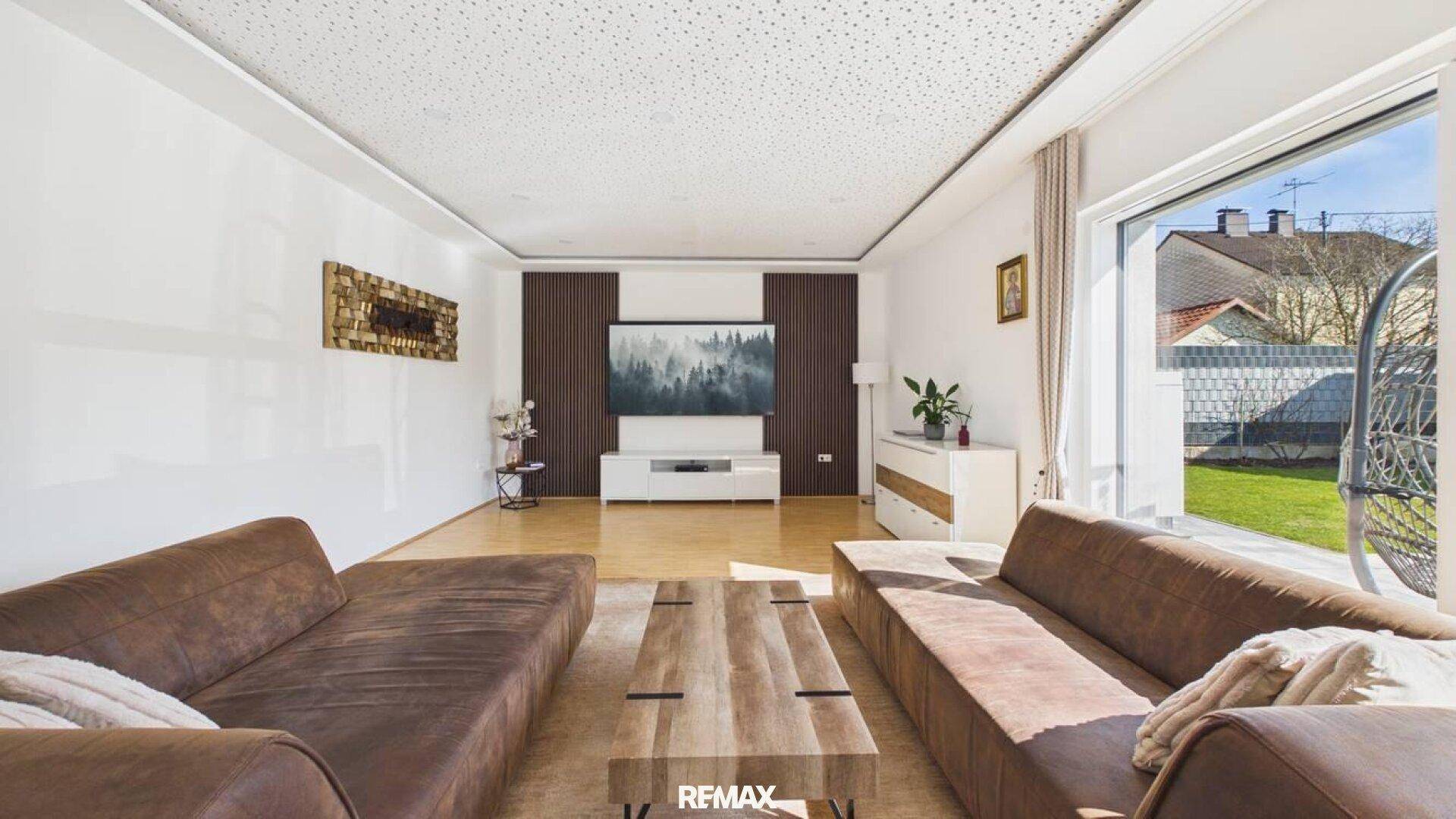 Helles Wohnzimmer mit bequemen Sofas, Holzboden und großem Fenster zum Garten.
