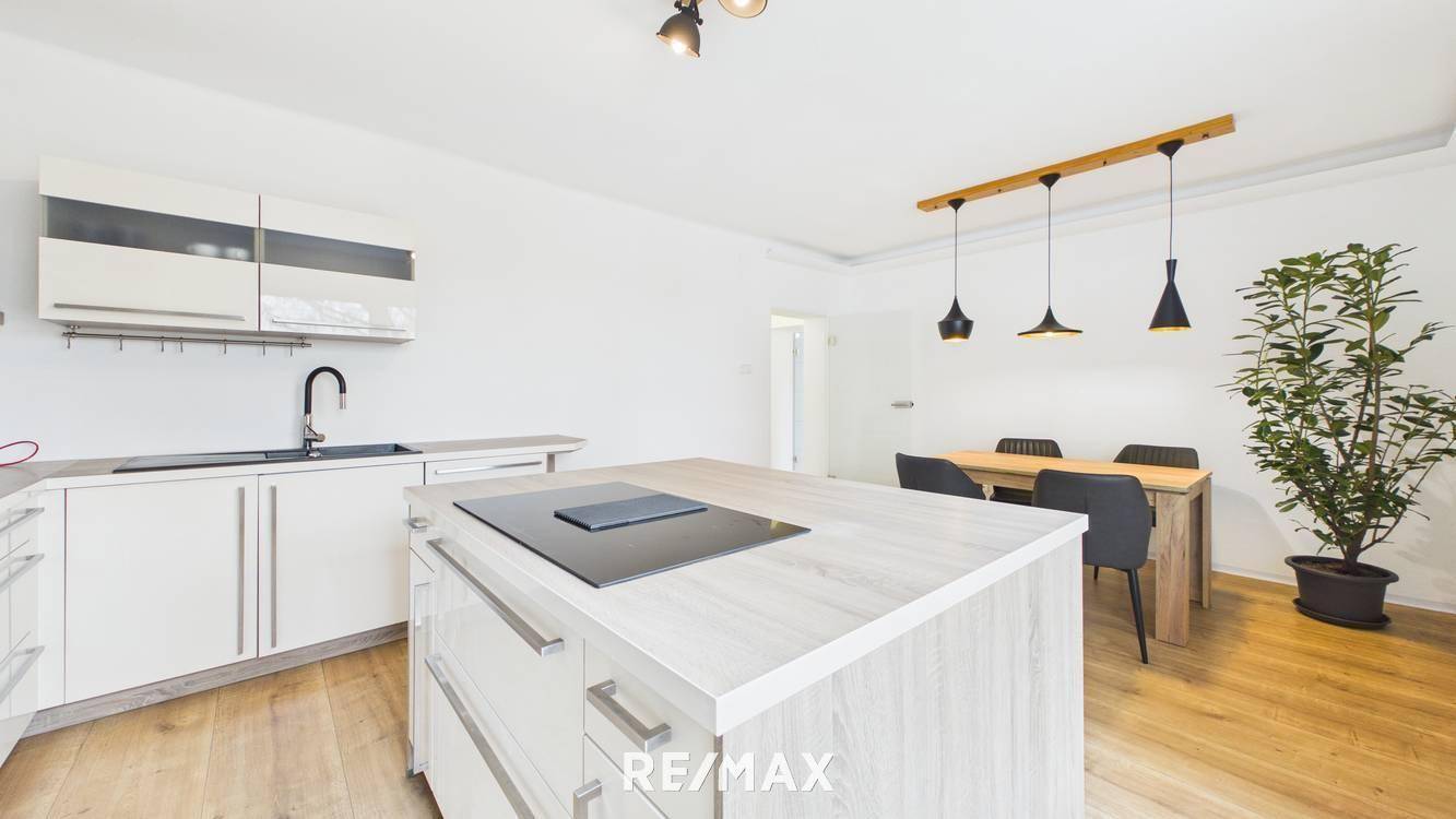 Moderne Einbauküche mit weißen Schränken, Spülbecken und einer funktionalen Kücheninsel.