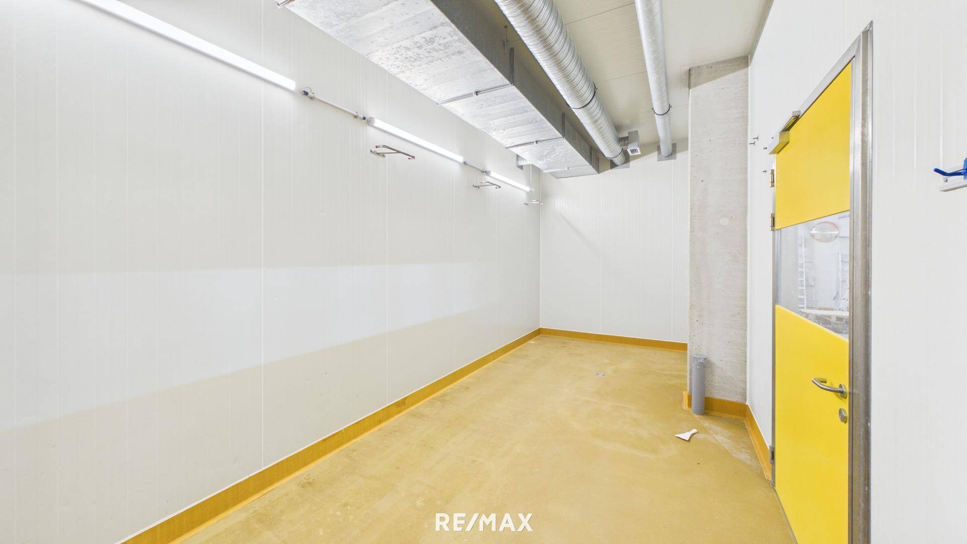 Kleinerer Lagerraum mit gelber Tür und sichtbaren Rohren an der Decke, funktional gestaltet.
