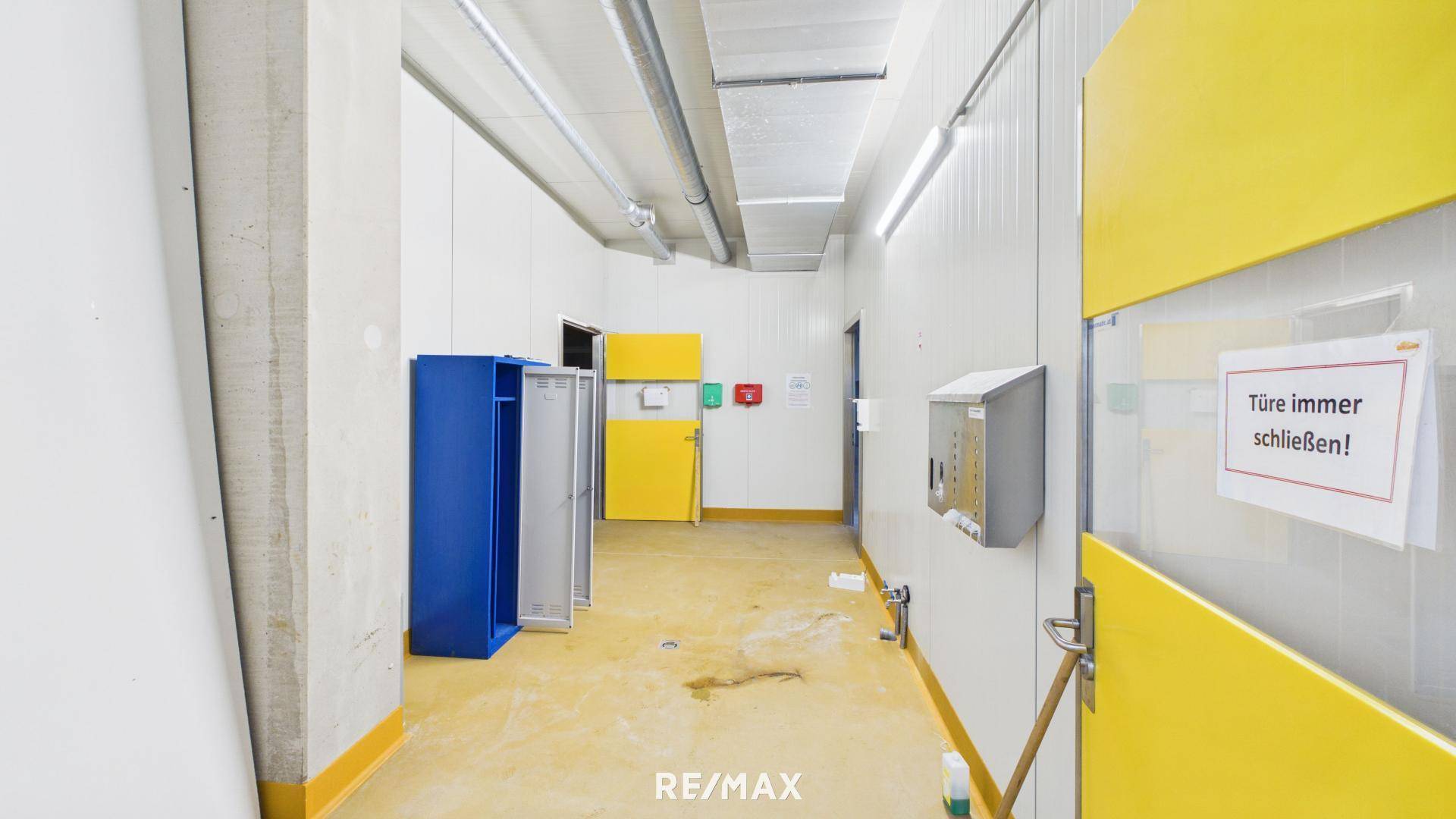 Flur mit blauen Spinden und gelben Türen, führt zu weiteren Räumen im Gebäude.