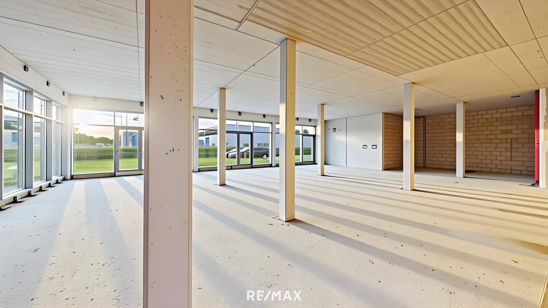Heller, weitläufiger Gewerberaum mit großen Fensterfronten, die viel Tageslicht hereinlassen.