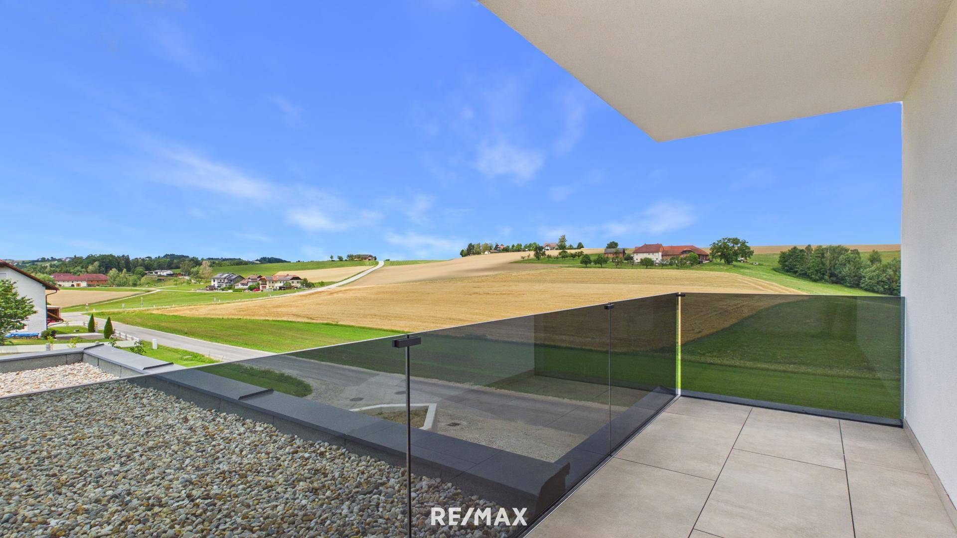 Balkon mit moderner Glasbrüstung bietet einen weiten Blick über die Felder und die ländliche Umgebung.