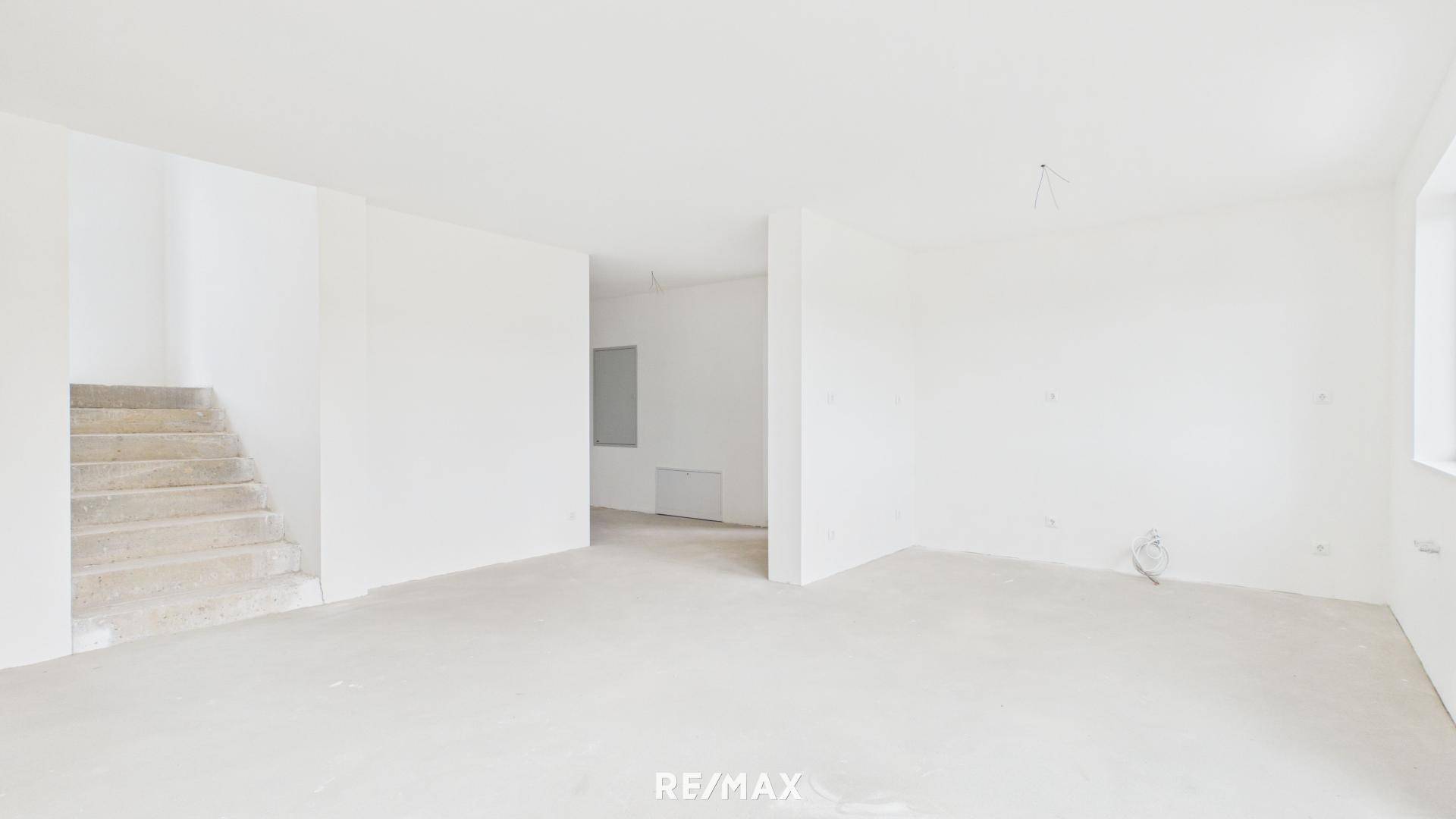 Geräumiger Wohnbereich im Rohbau mit Treppenaufgang und viel Potenzial zur Gestaltung.