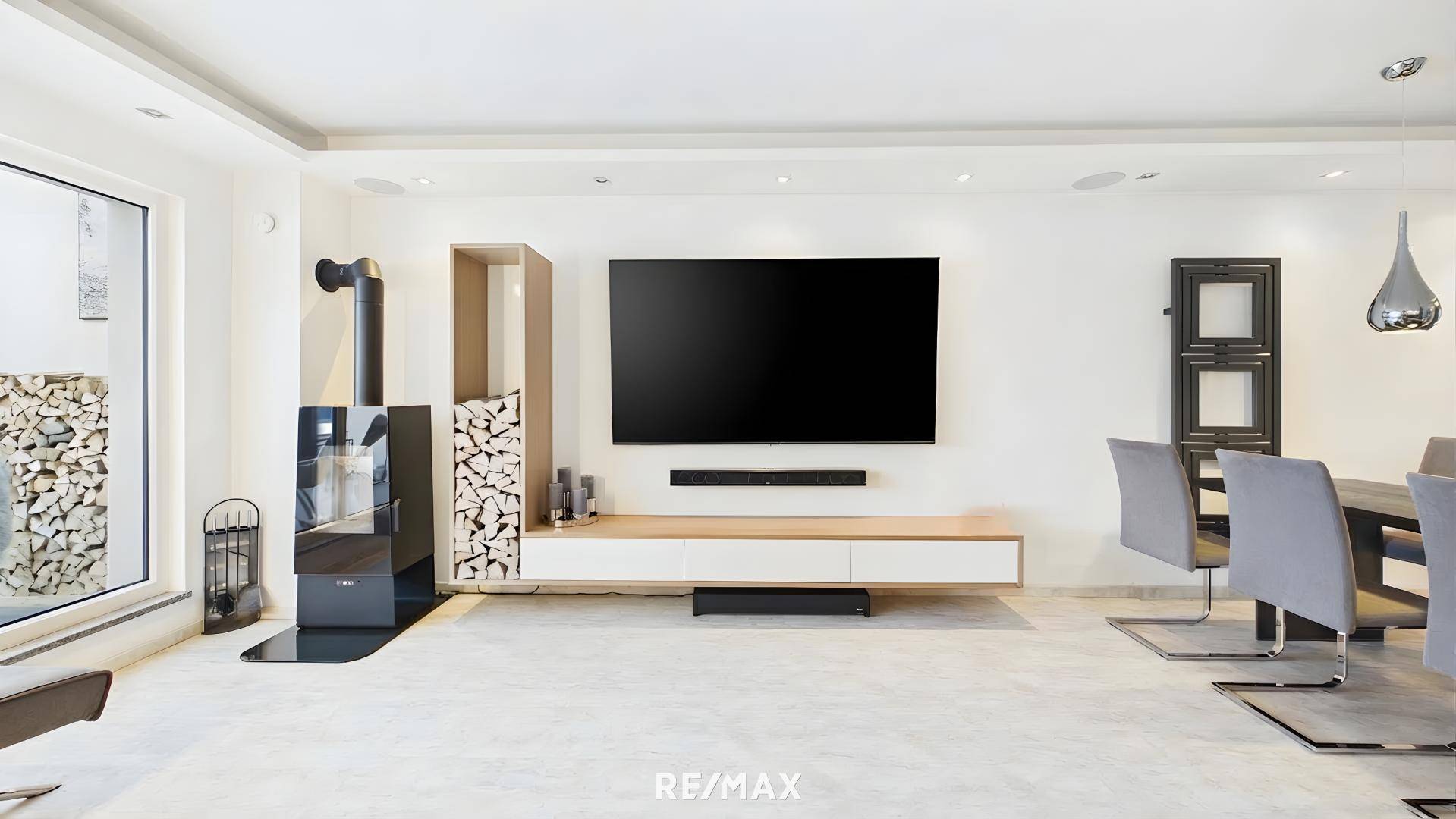 Wohnzimmerwand mit großem Fernseher, modernem Kamin und Holzstapel als Dekoration.