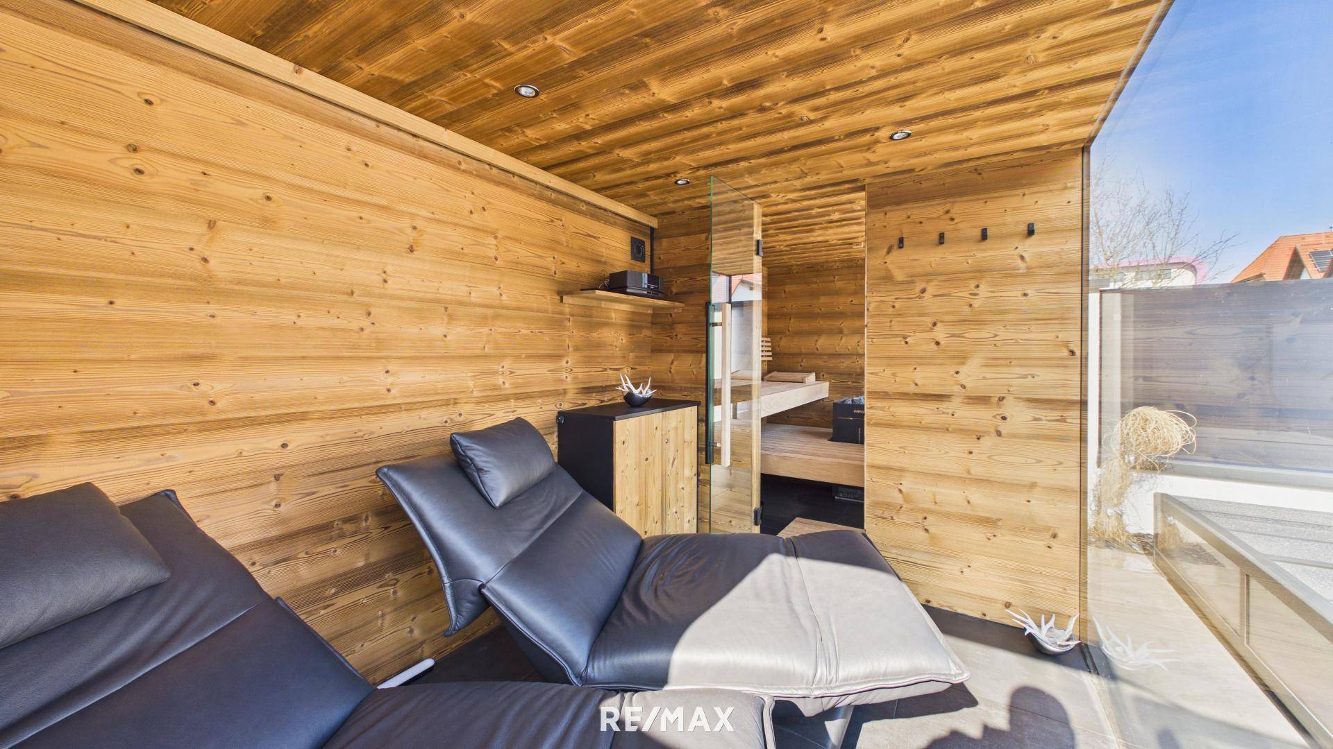 Entspannungsbereich mit Holzvertäfelung, bequemen Liegen und Zugang zur Sauna.