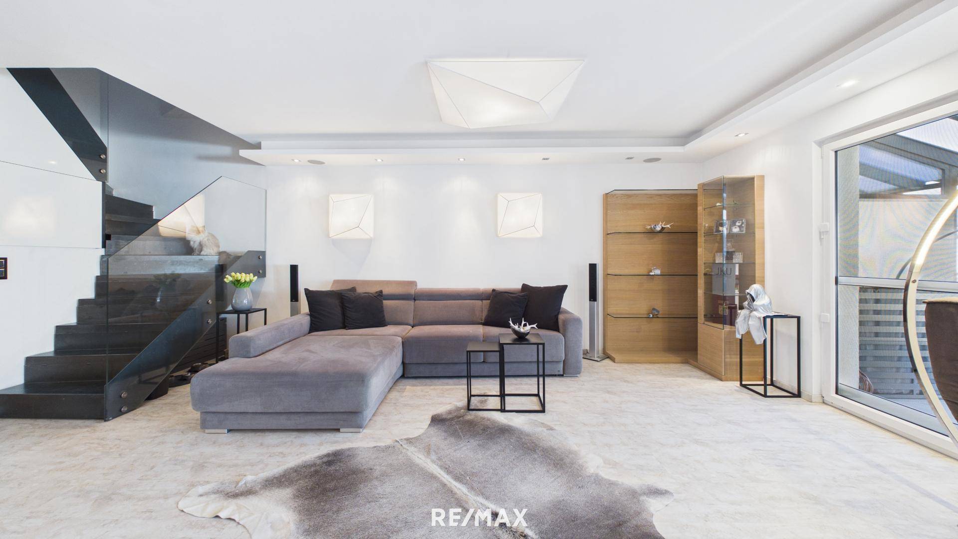 Geräumiges Wohnzimmer mit bequemer Eckcouch, moderner Treppe und hellem Ambiente.
