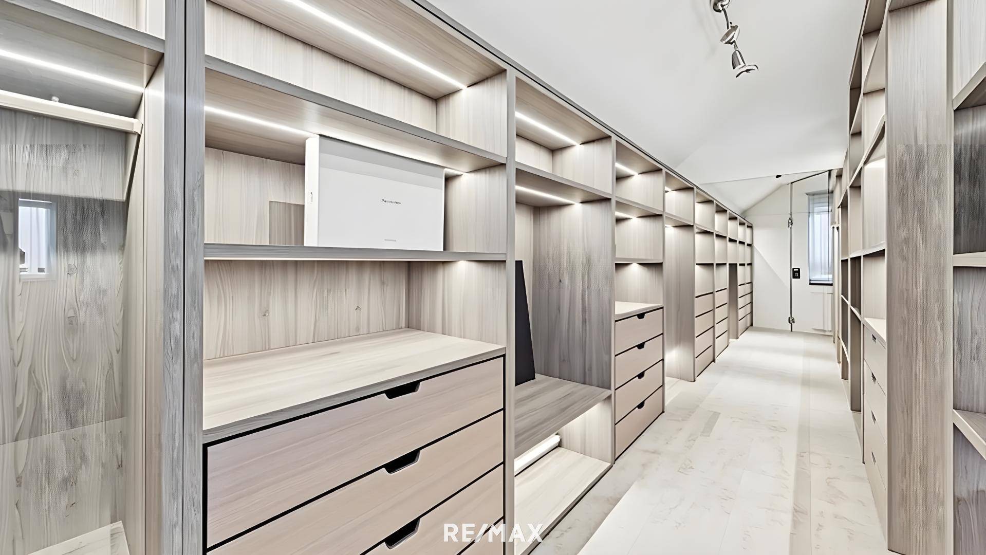 Geräumiger begehbarer Kleiderschrank mit integrierten Regalen und Schubladen.
