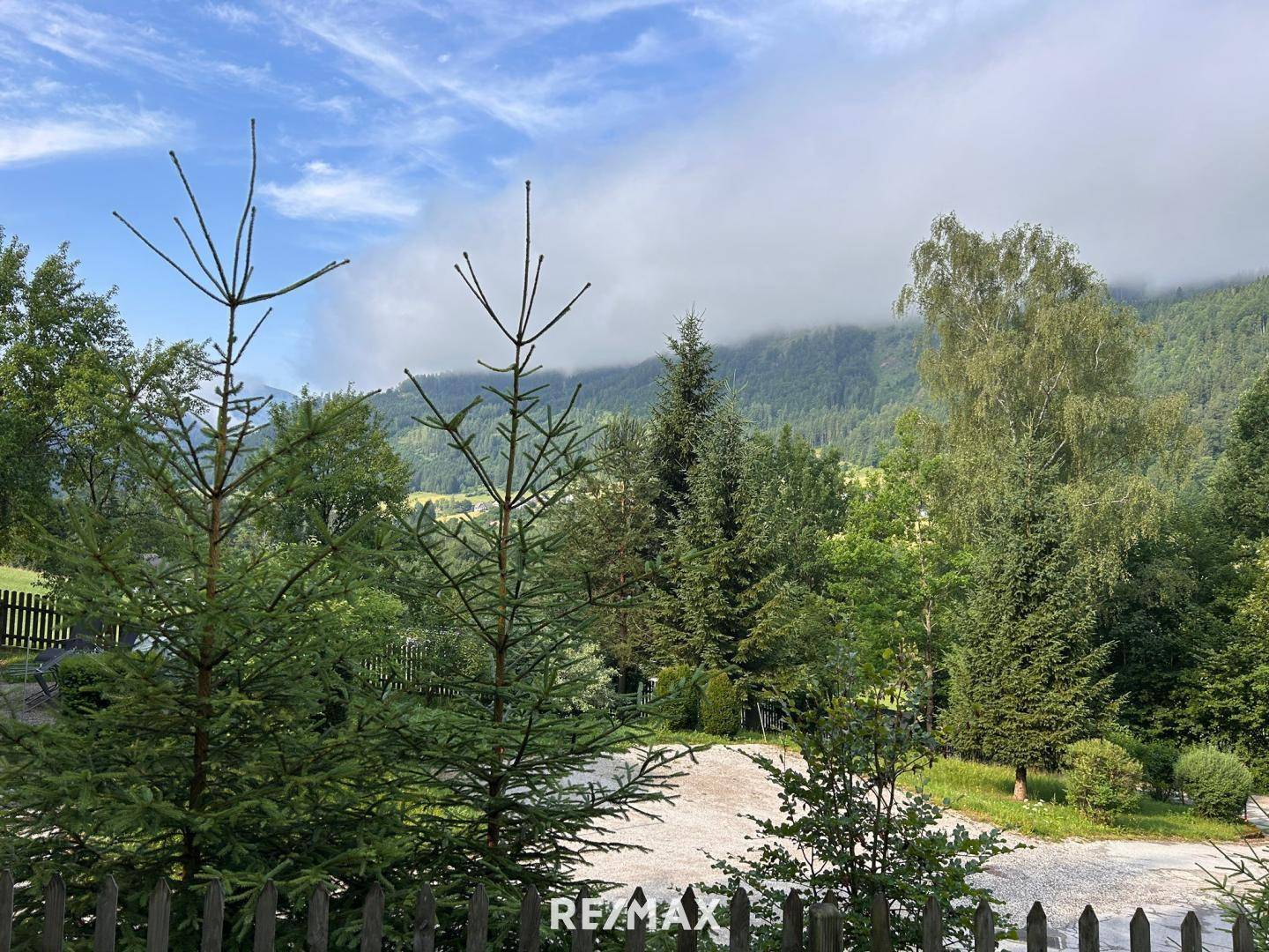 Malerischer Ausblick auf bewaldete Berge und grüne Landschaft unter bewölktem Himmel.