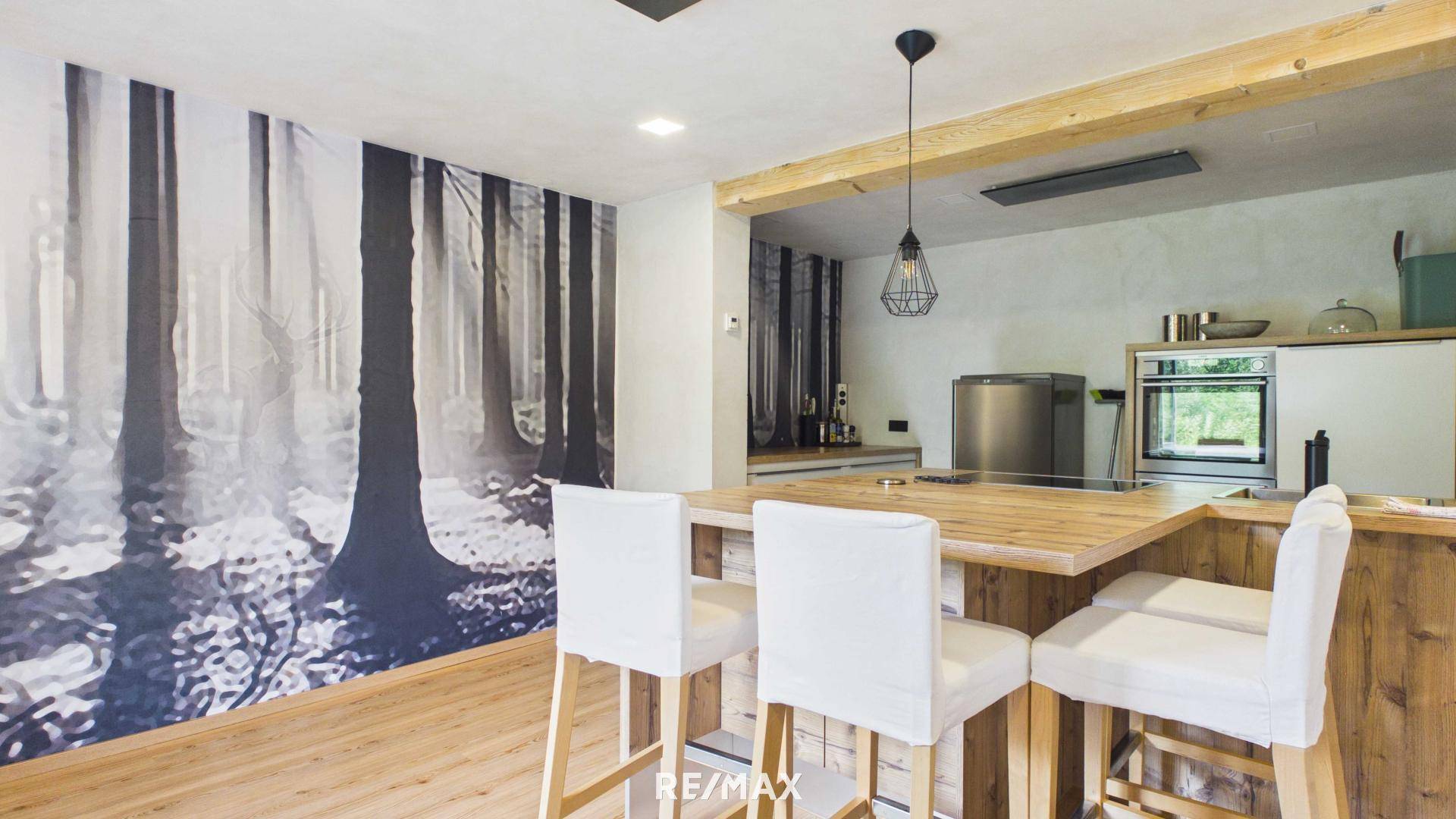 Offene Küche mit Holztheke und Barhockern, kombiniert mit einem Essbereich.