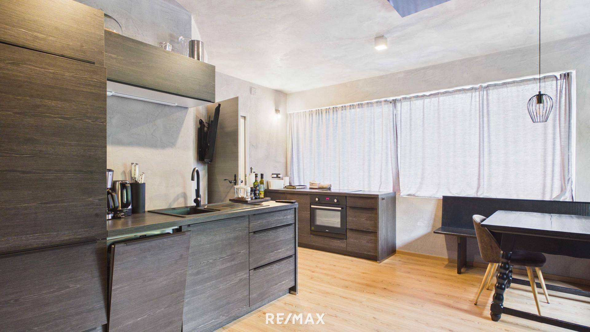 Moderne Holzküche mit integrierten Geräten und einem Essbereich im Hintergrund.