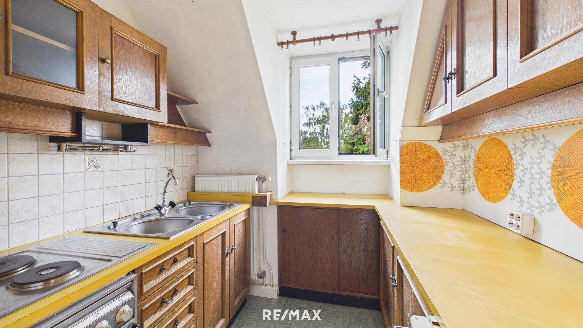 Kleine Küche im Dachgeschoss mit gelben Arbeitsplatten, Holzschränken und Dachfenster.