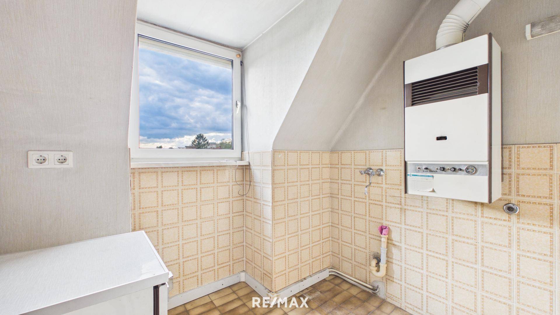 Kleiner Hauswirtschaftsraum im Dachgeschoss mit Gastherme und gefliesten Wänden, funktional und praktisch.