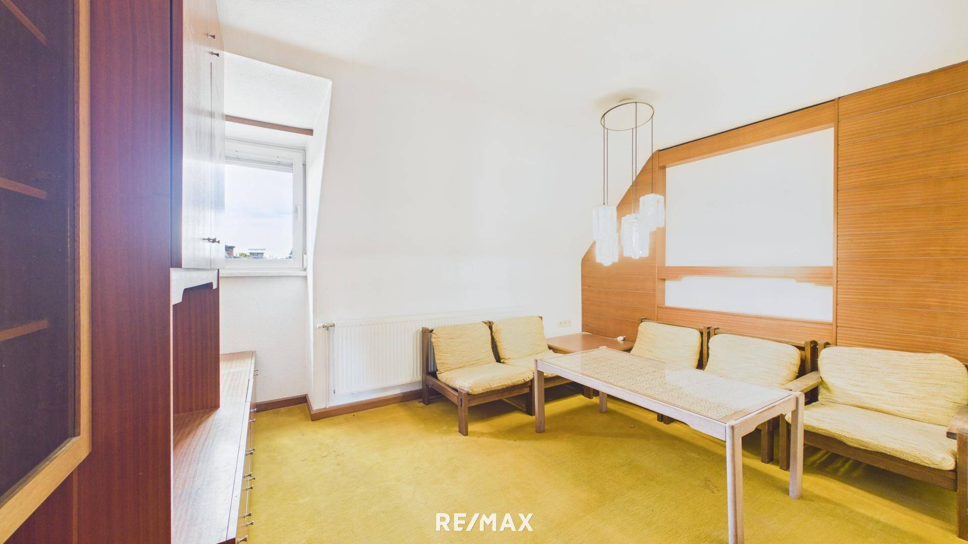 Wohnzimmer mit gelbem Teppichboden, Holzvertäfelung und Sitzmöbeln, bietet viel Platz.