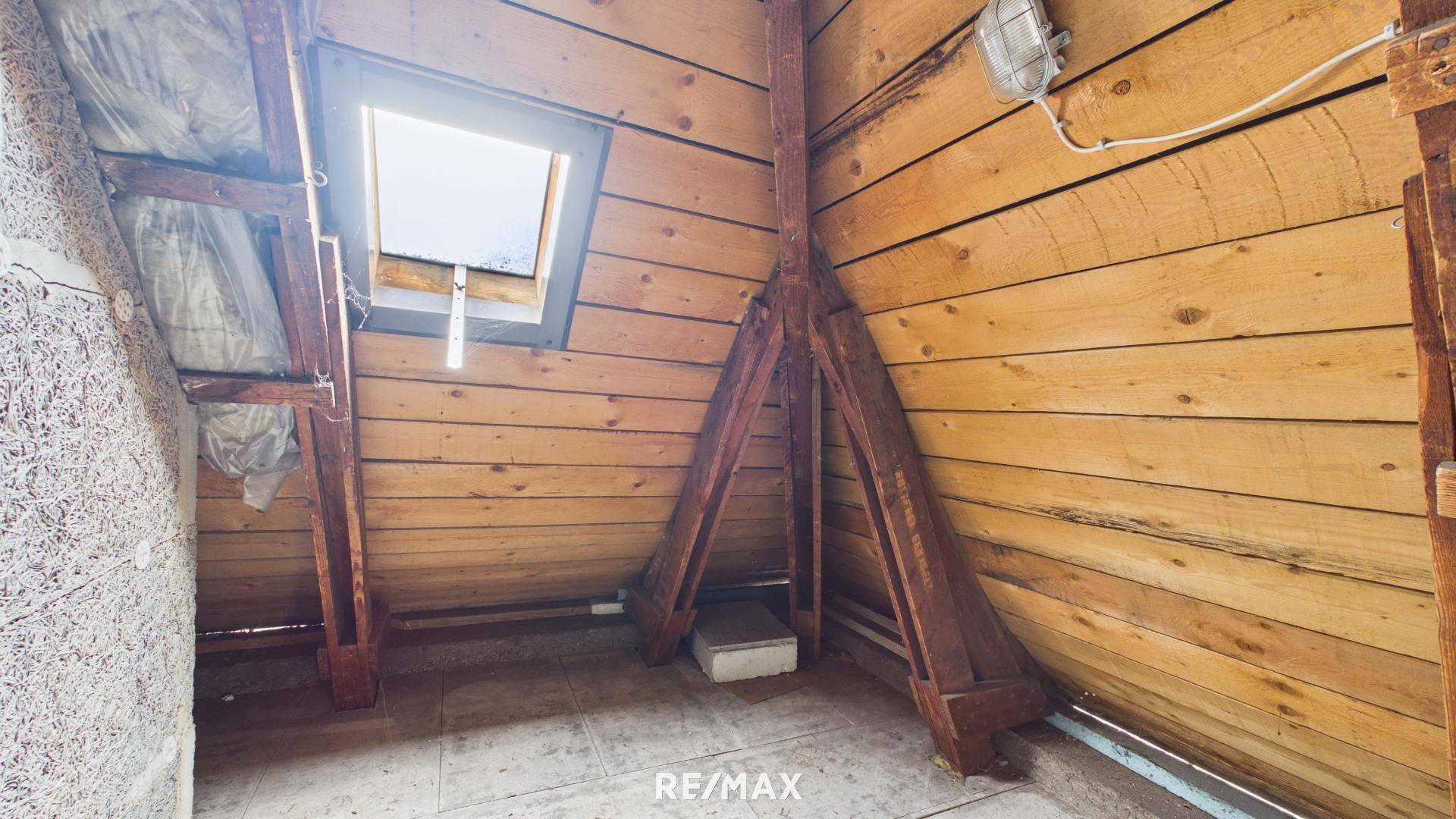 Unausgebauter Dachboden mit Holzbalken und Dachfenster, bietet Ausbaupotenzial.