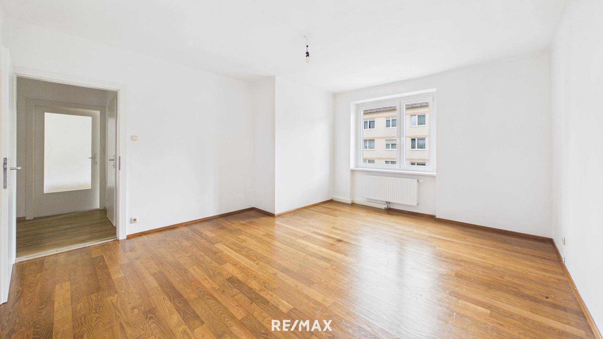 Lichtdurchflutetes Zimmer mit Holzboden und Blick auf die Umgebung, ideal für ein Schlafzimmer.