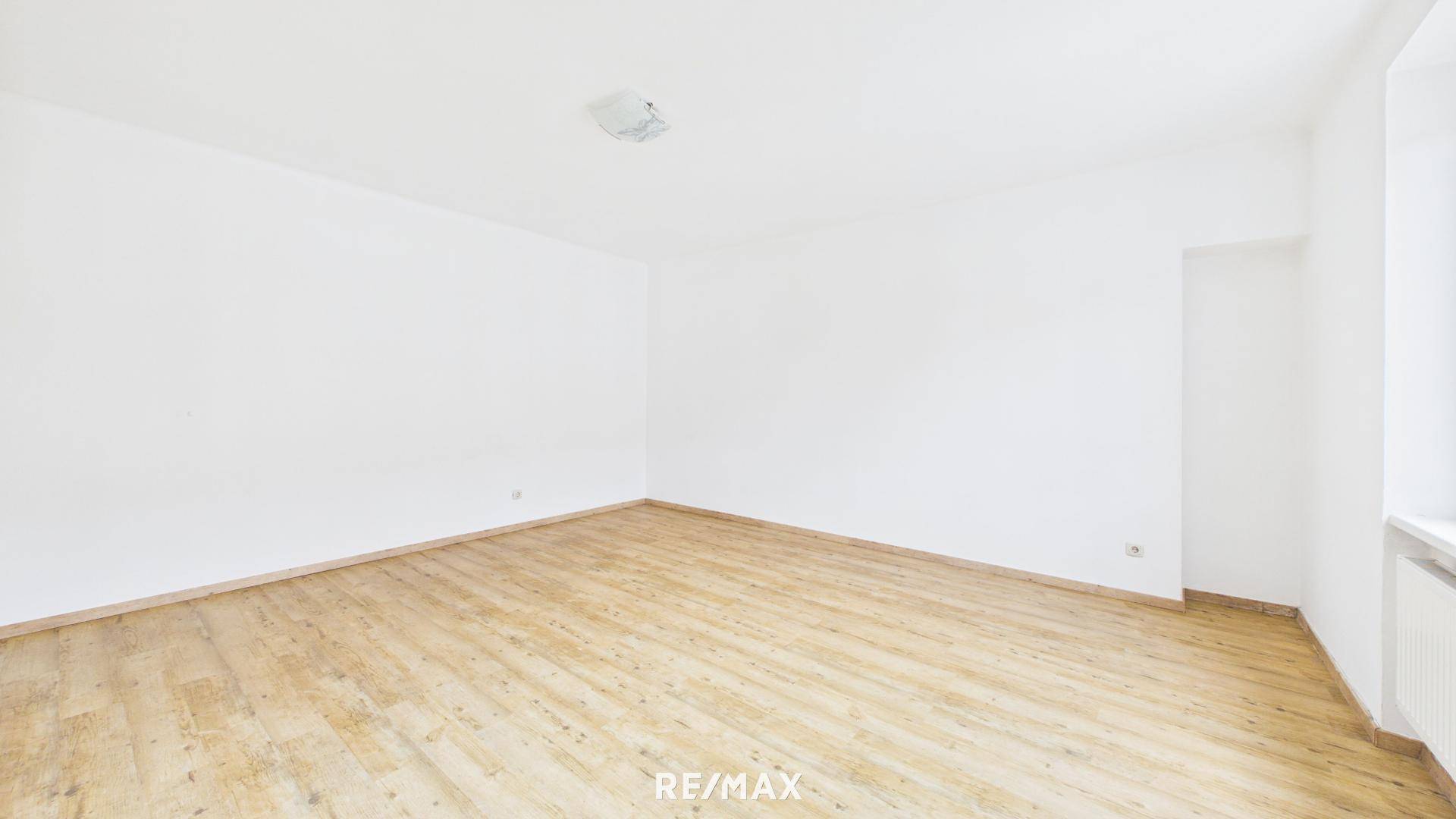 Heller Raum mit Laminatboden und weißen Wänden, bietet vielseitige Nutzungsmöglichkeiten.