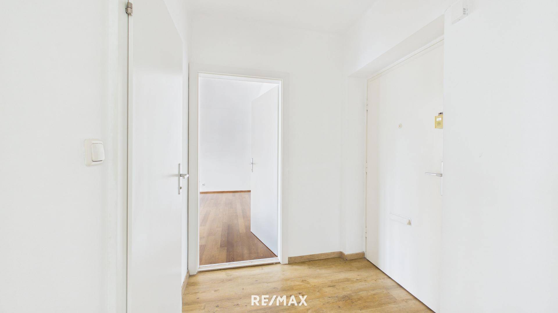 Heller Flur mit Laminatboden und weißen Türen, verbindet die verschiedenen Wohnbereiche der Wohnung.